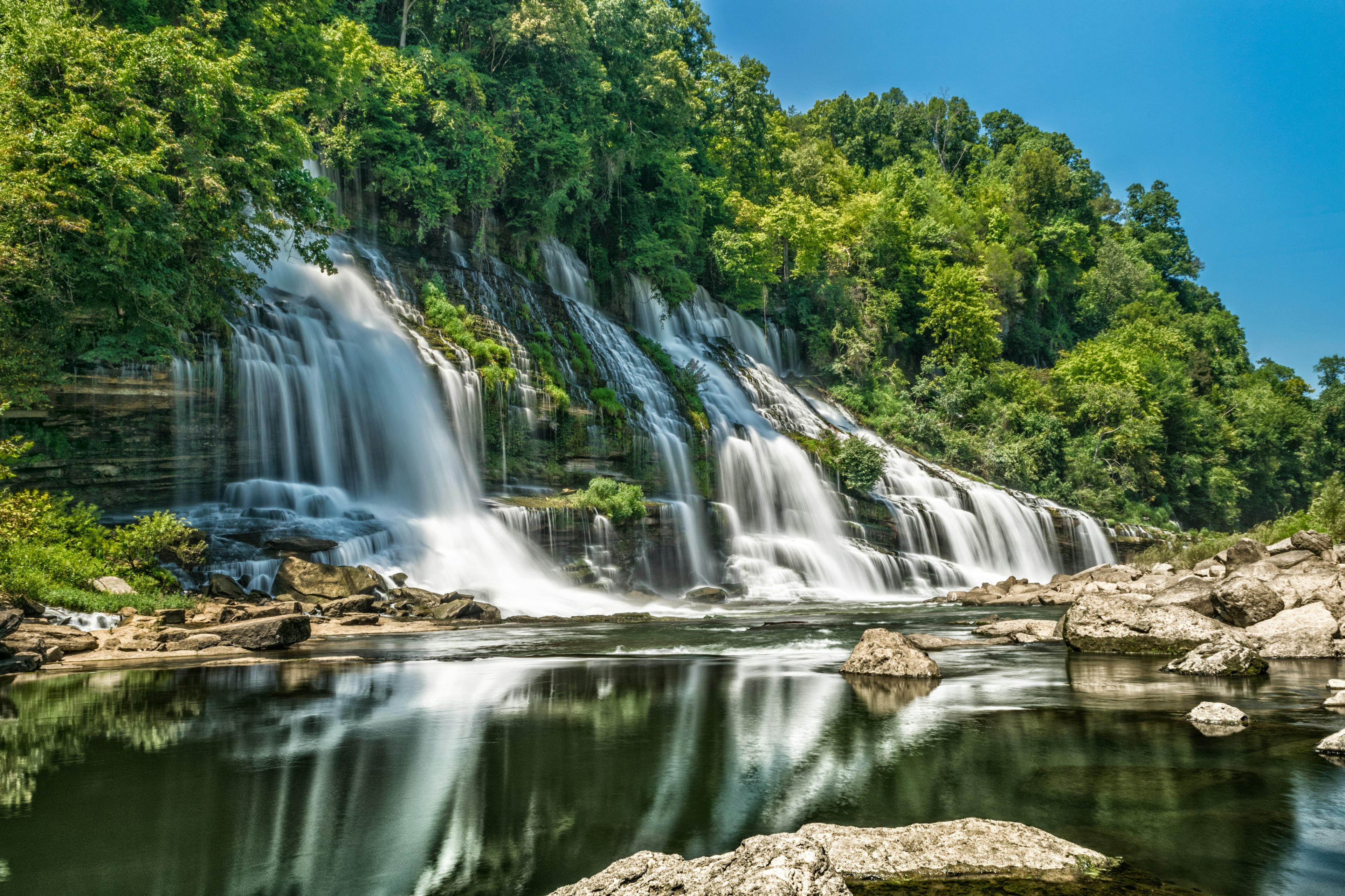 Upstream view of Twin Falls waterfall and the surrounding lush foliage in Rock Island State Park