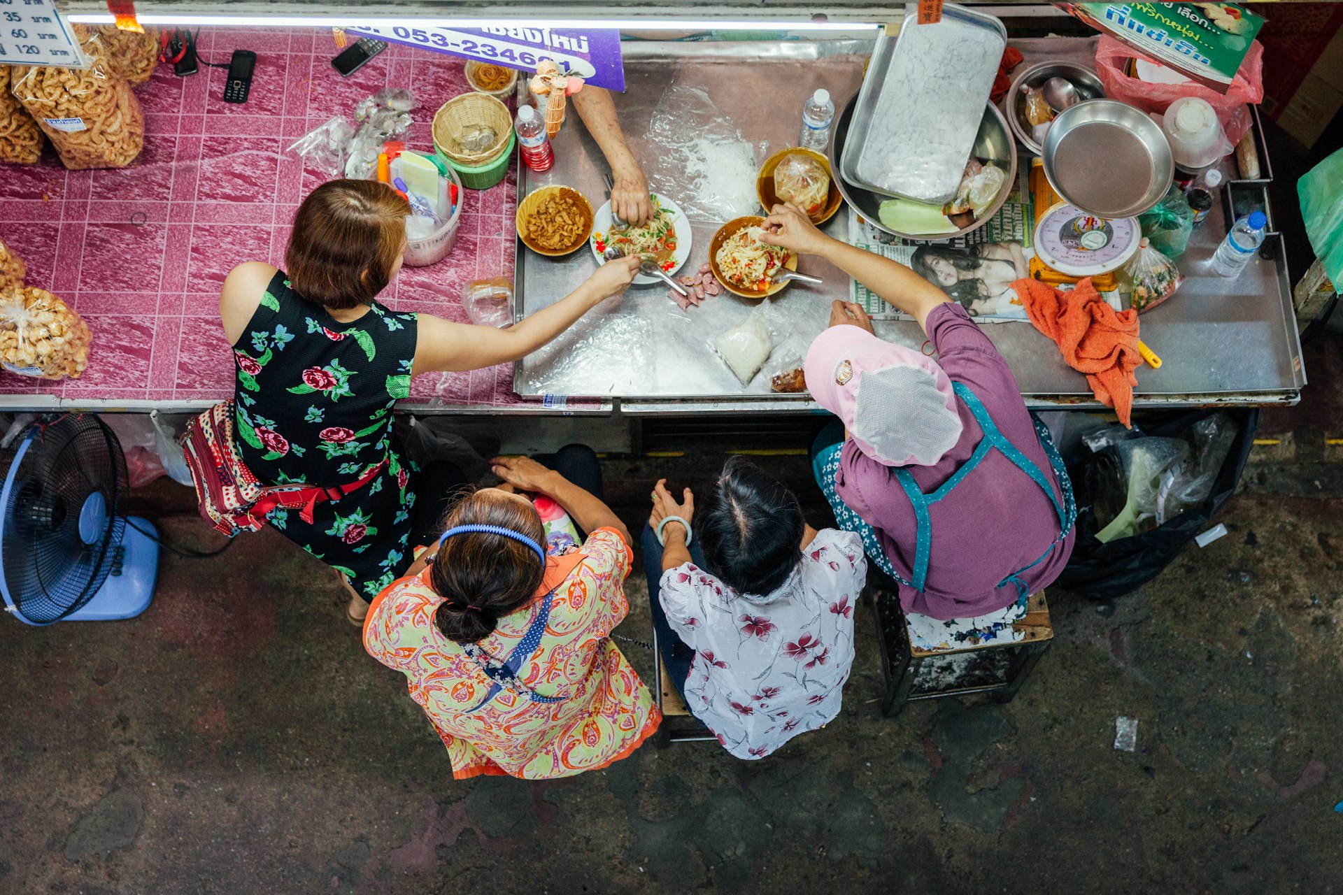 Overhead shot of a group of people eating Thai food for lunch at the Warorot Market in Chiang Mai. 