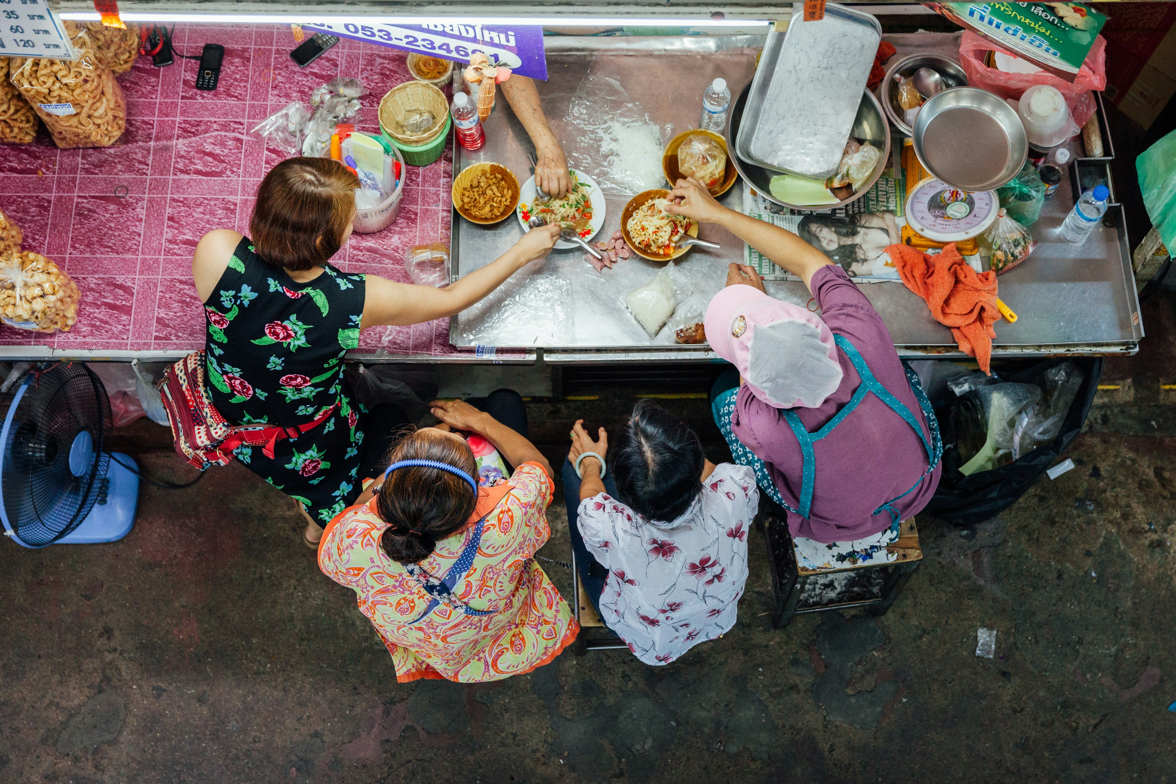 Overhead shot of a group of people eating Thai food for lunch at the Warorot Market in Chiang Mai.