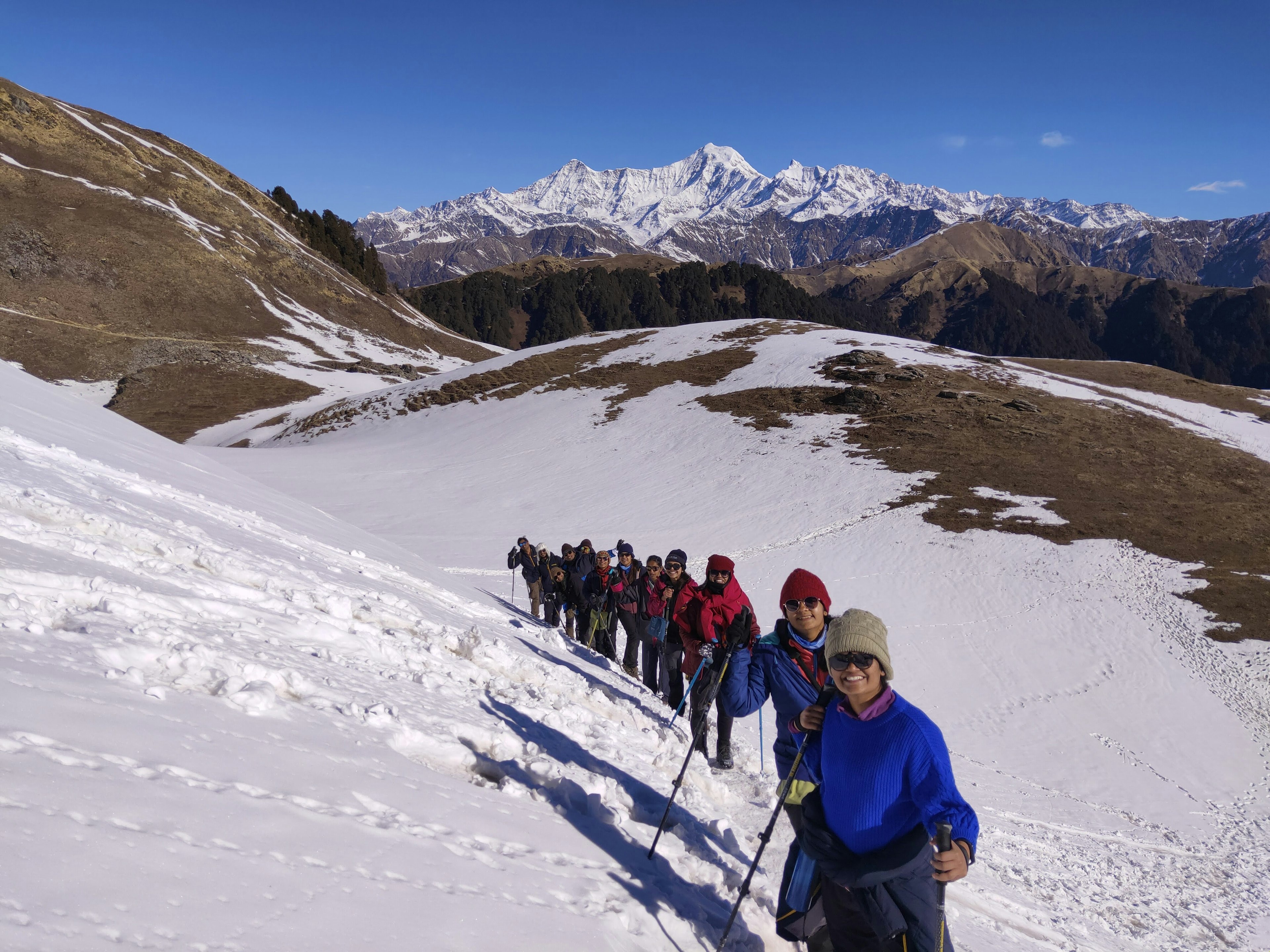 IMG20230224091420_Original.jpga group of hikers smile as a standard a line up on a snowy mountain