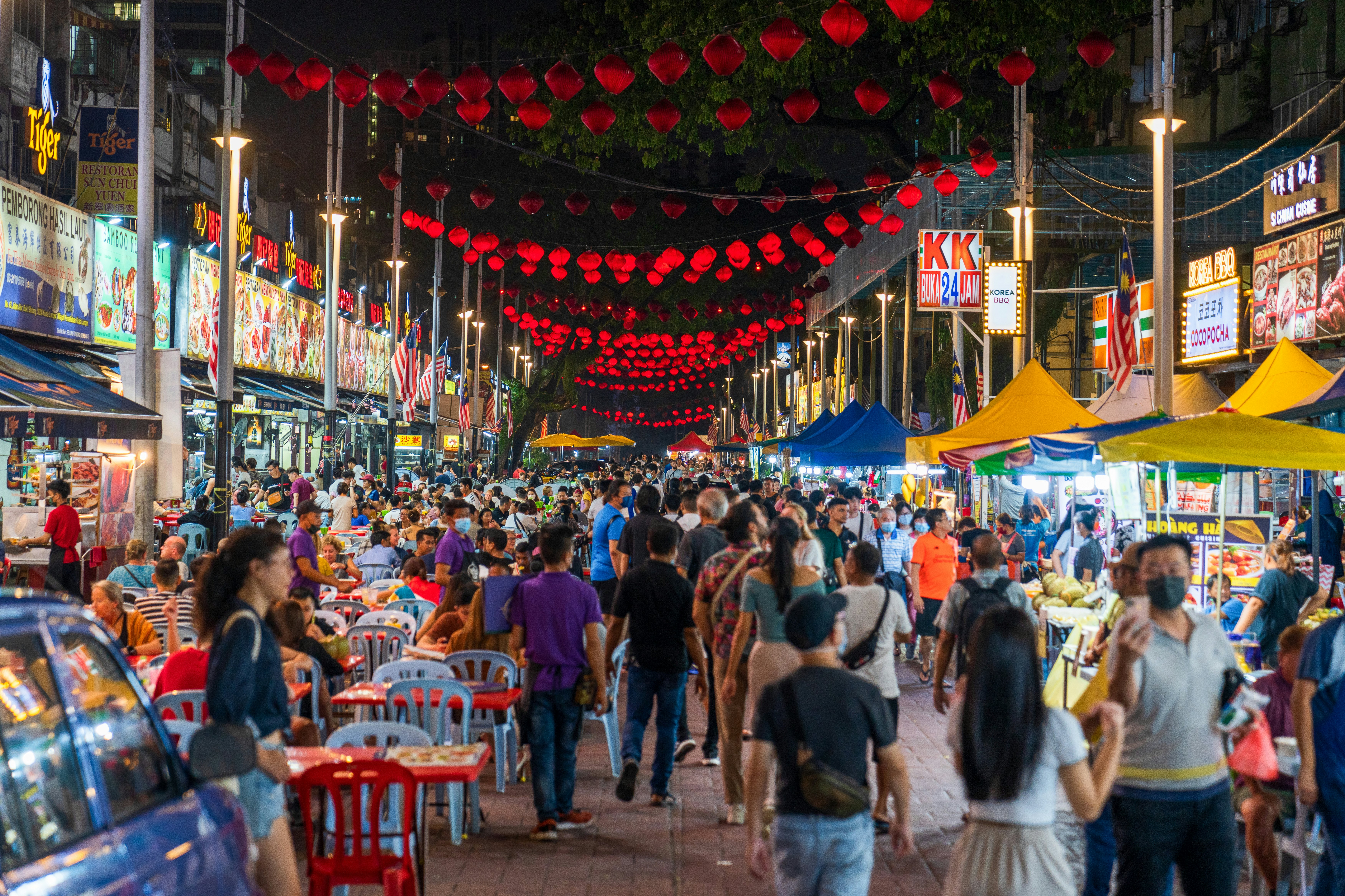 A busy street lined with food stalls and decorated with red lanterns