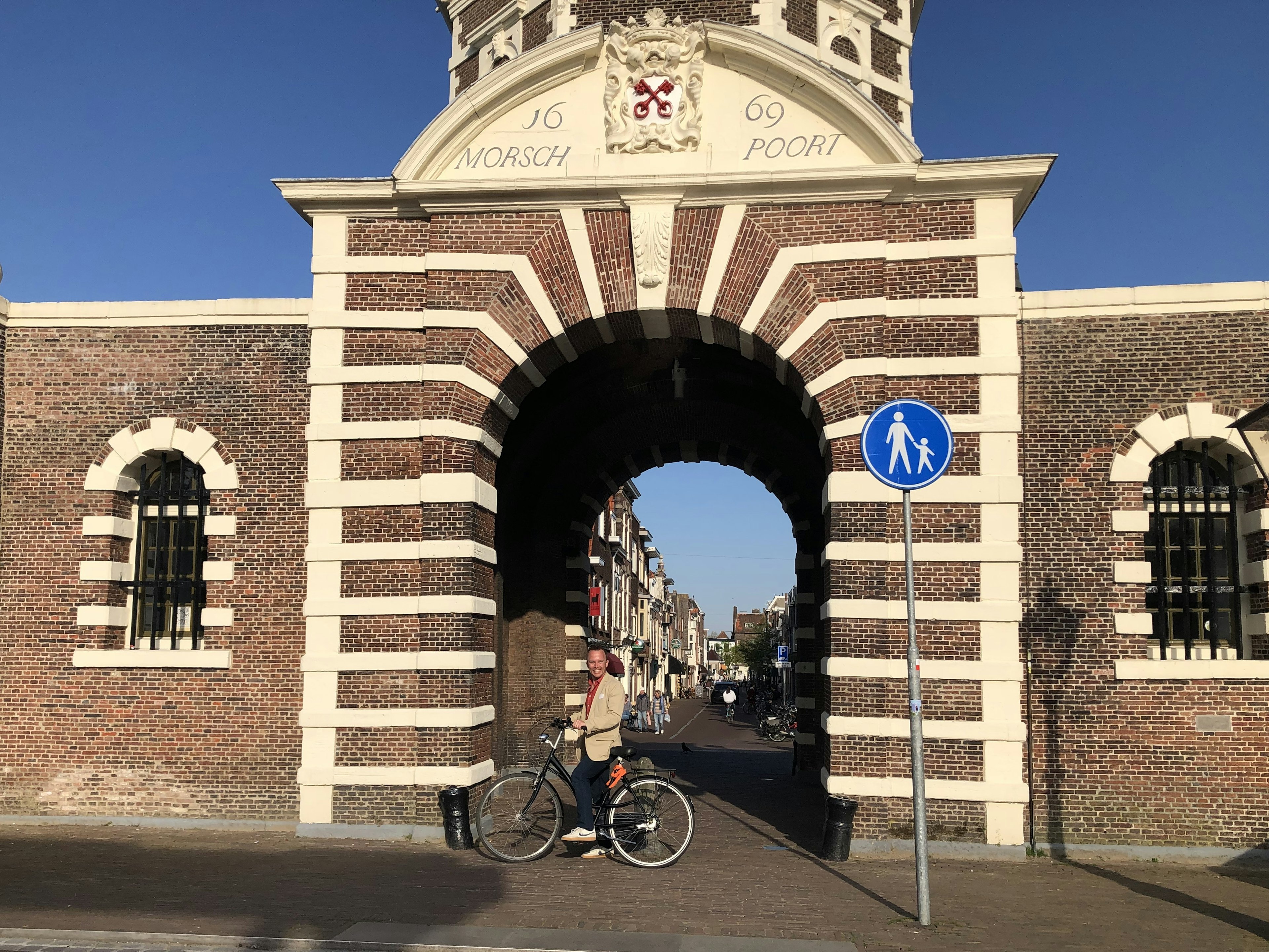 Writer Brian Healy stands with his bike in a brick archway in Leiden