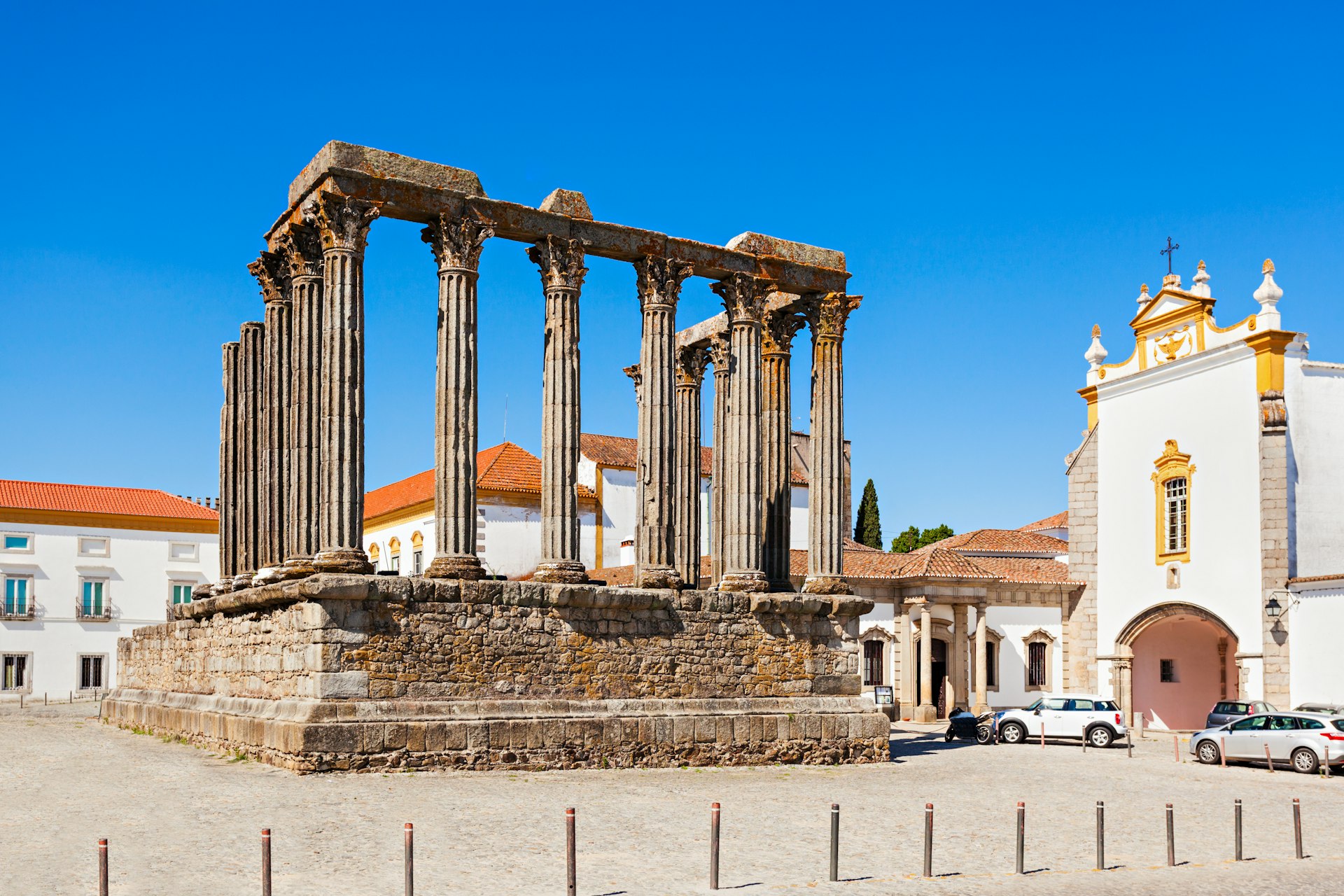 A large columned Roman structure stands in the center of a town square