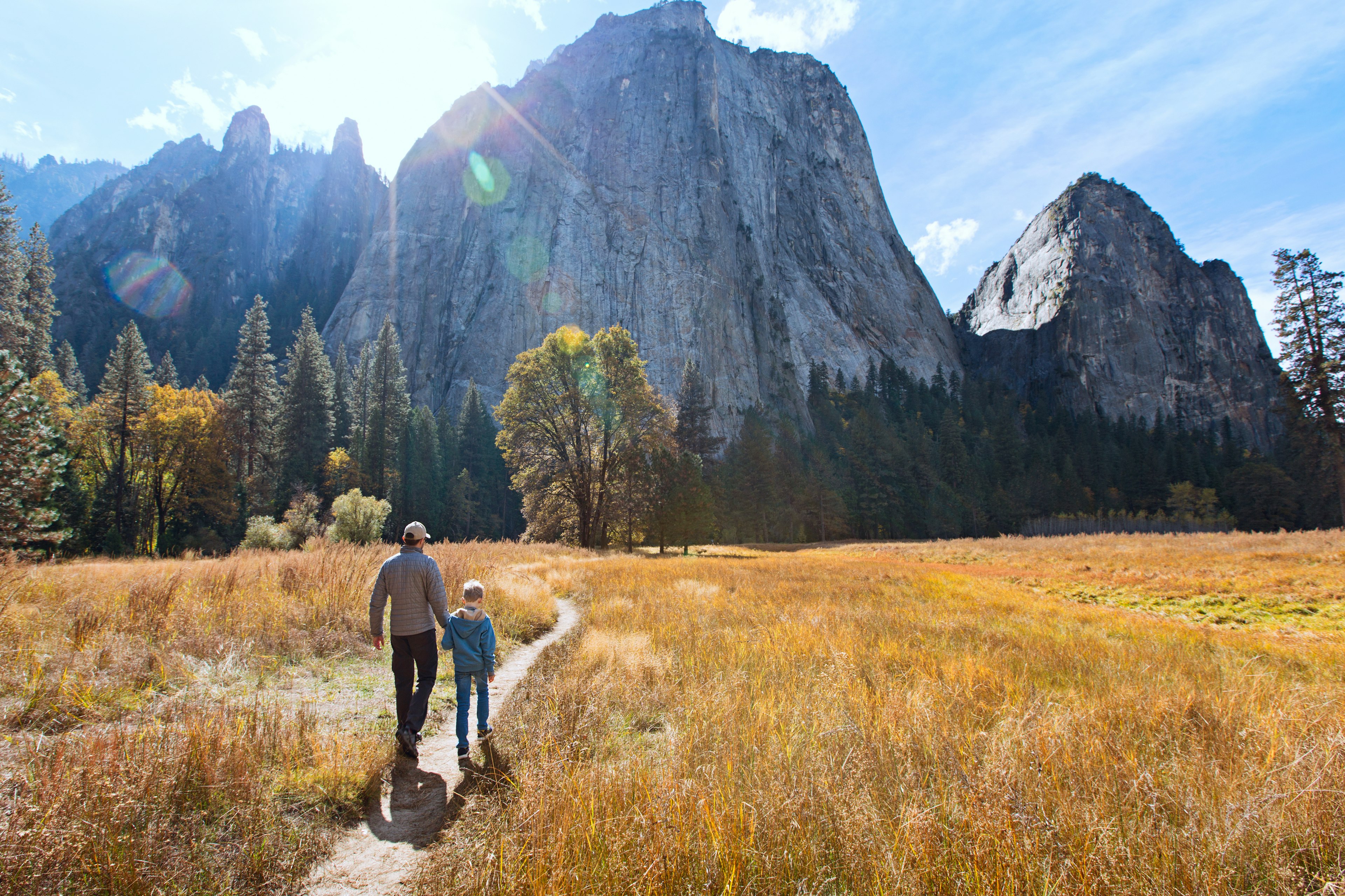 Back view of active family of two, father and son, enjoying valley and mountain view in Yosemite National Park, California