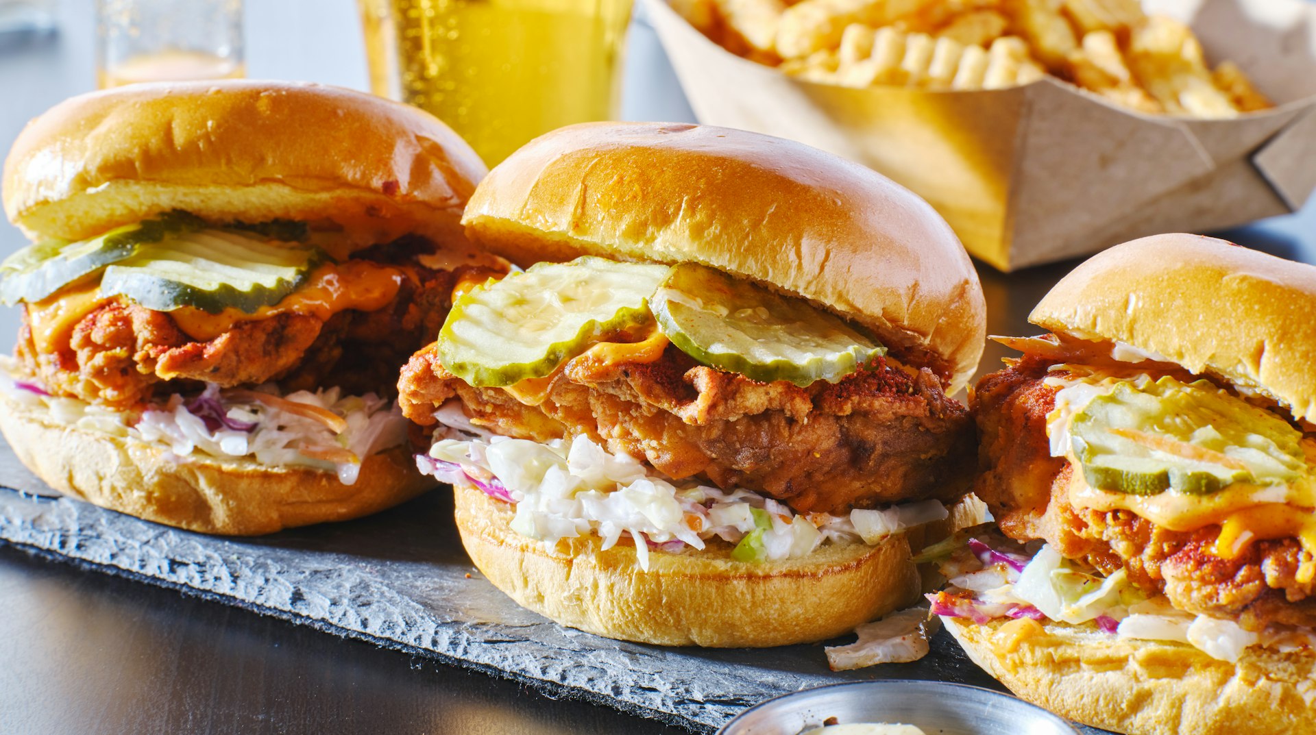 A trio of spicy Nashville hot chicken sandwiches with coleslaw and pickles
