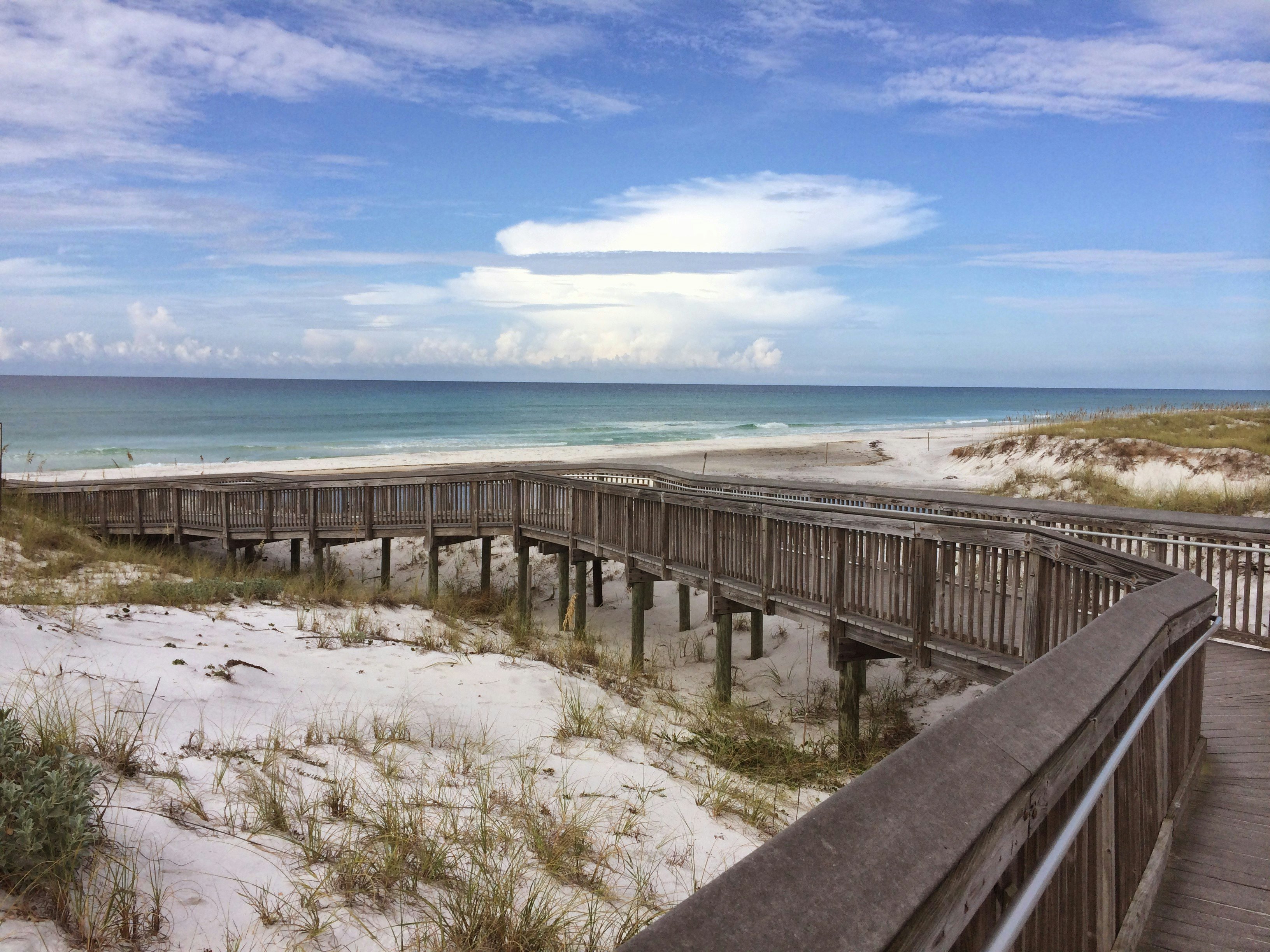 A boardwalk over sandy dunes by the sea in Florida.