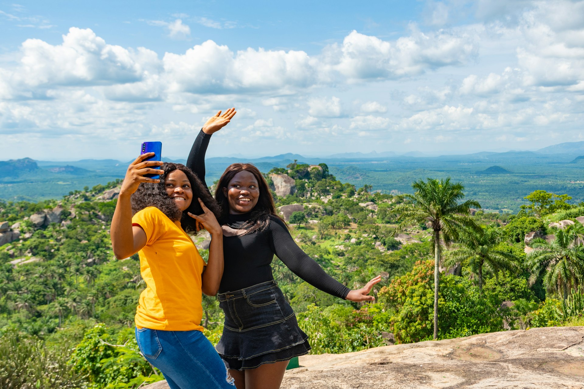 young female african friends standing together outdoor on a hike through nature taking selfies