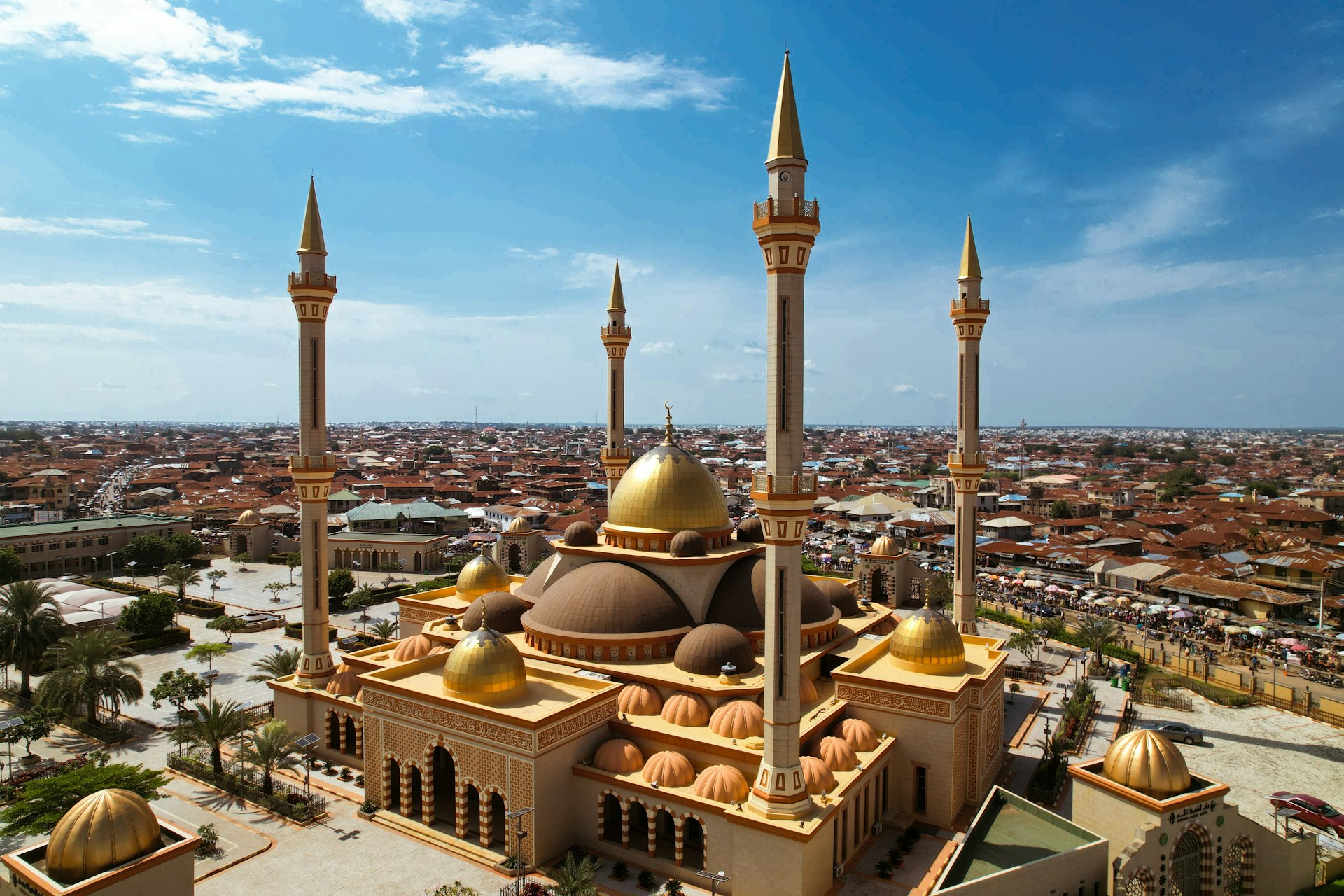 A vast beautiful gold-and-brown mosque with many central domes and four tall minarets