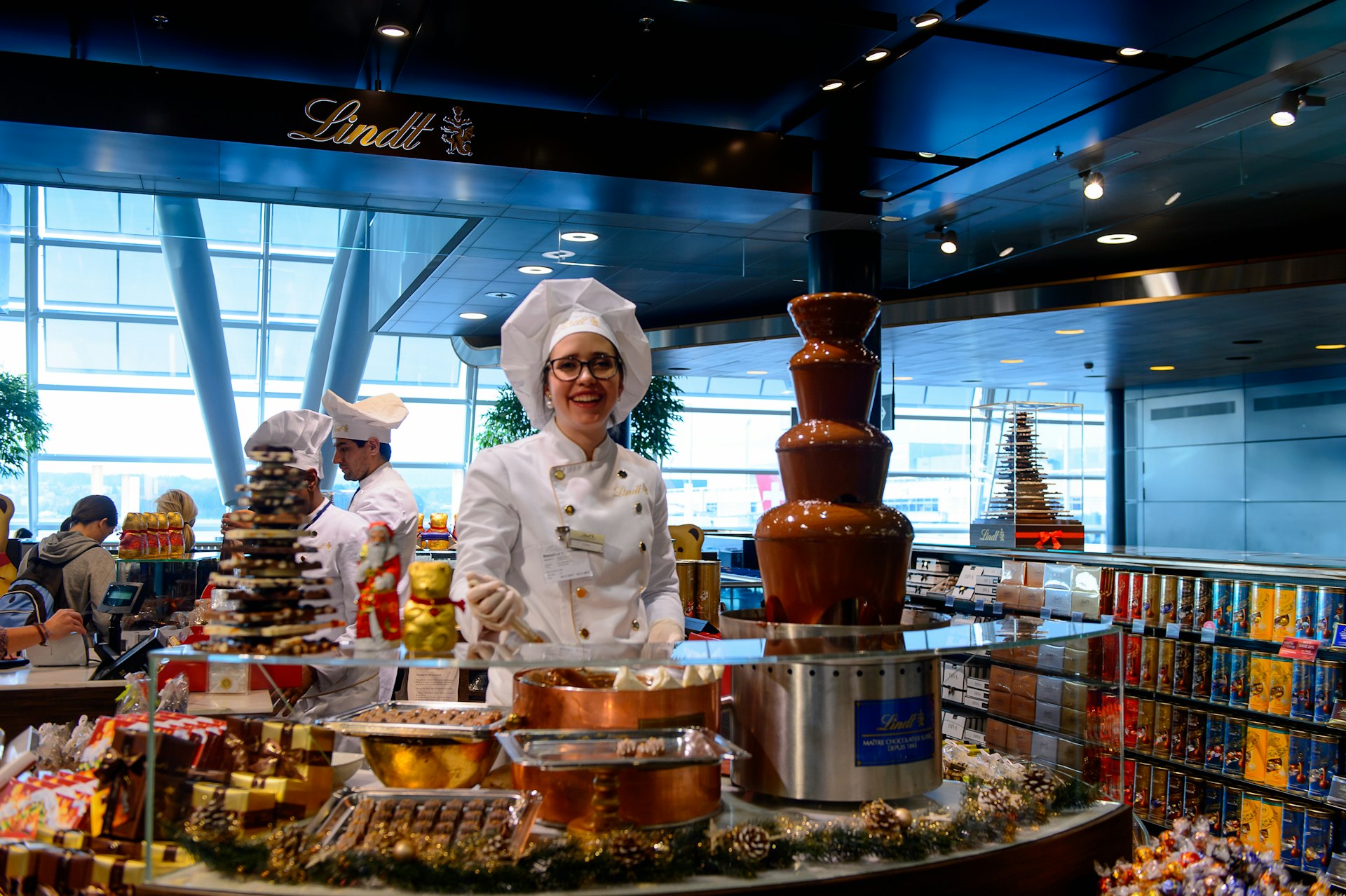 Retailer of Christmas chocolate smiled behind the a counter full of chocolates in Switzerland 