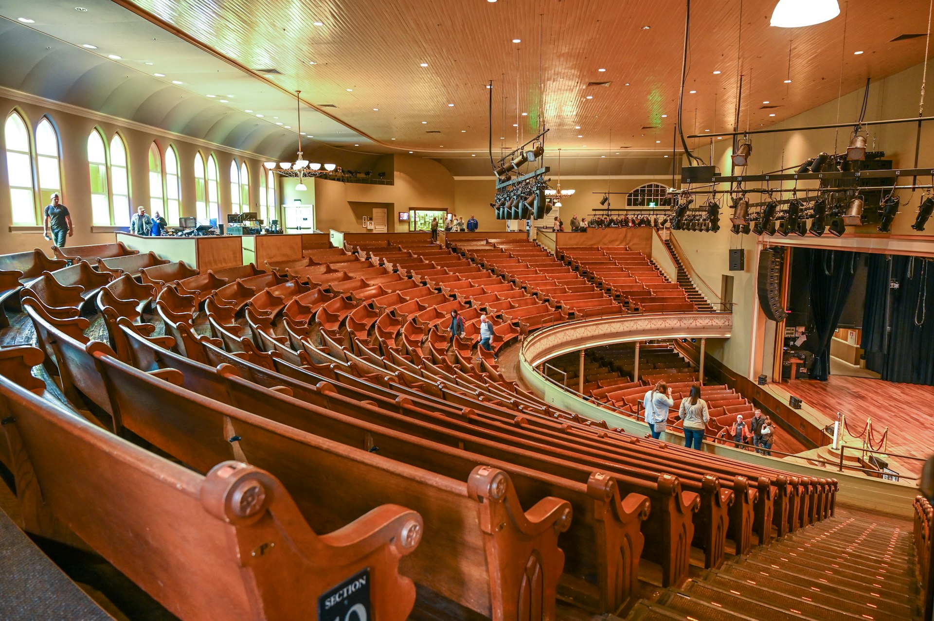 Interior of legendary Ryman Auditorium, seen from the back of the balcony looking out over rows of wooden seats and the stage 