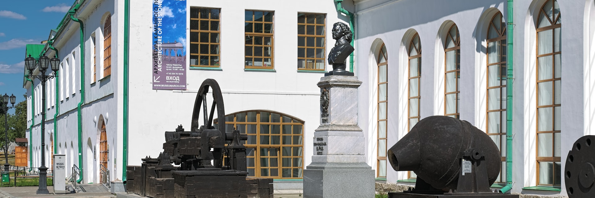Bust of Peter I outside the Museum of Architecture and Design surrounded by iron plants equipment. 