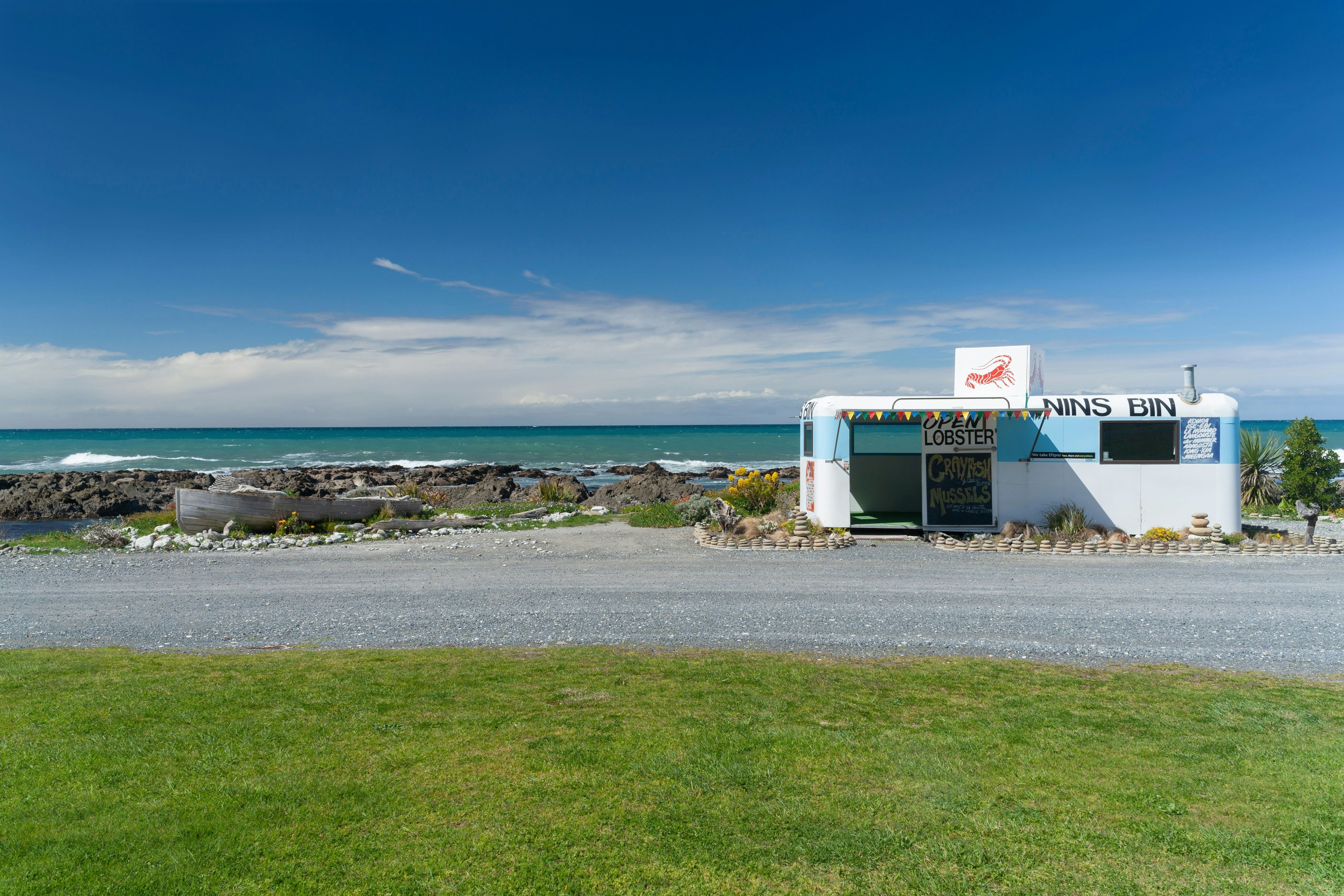 The Best Foodie Destinations for Culinary Travel A roadside seafood restaurant in a blue truck with the coastline in the background.