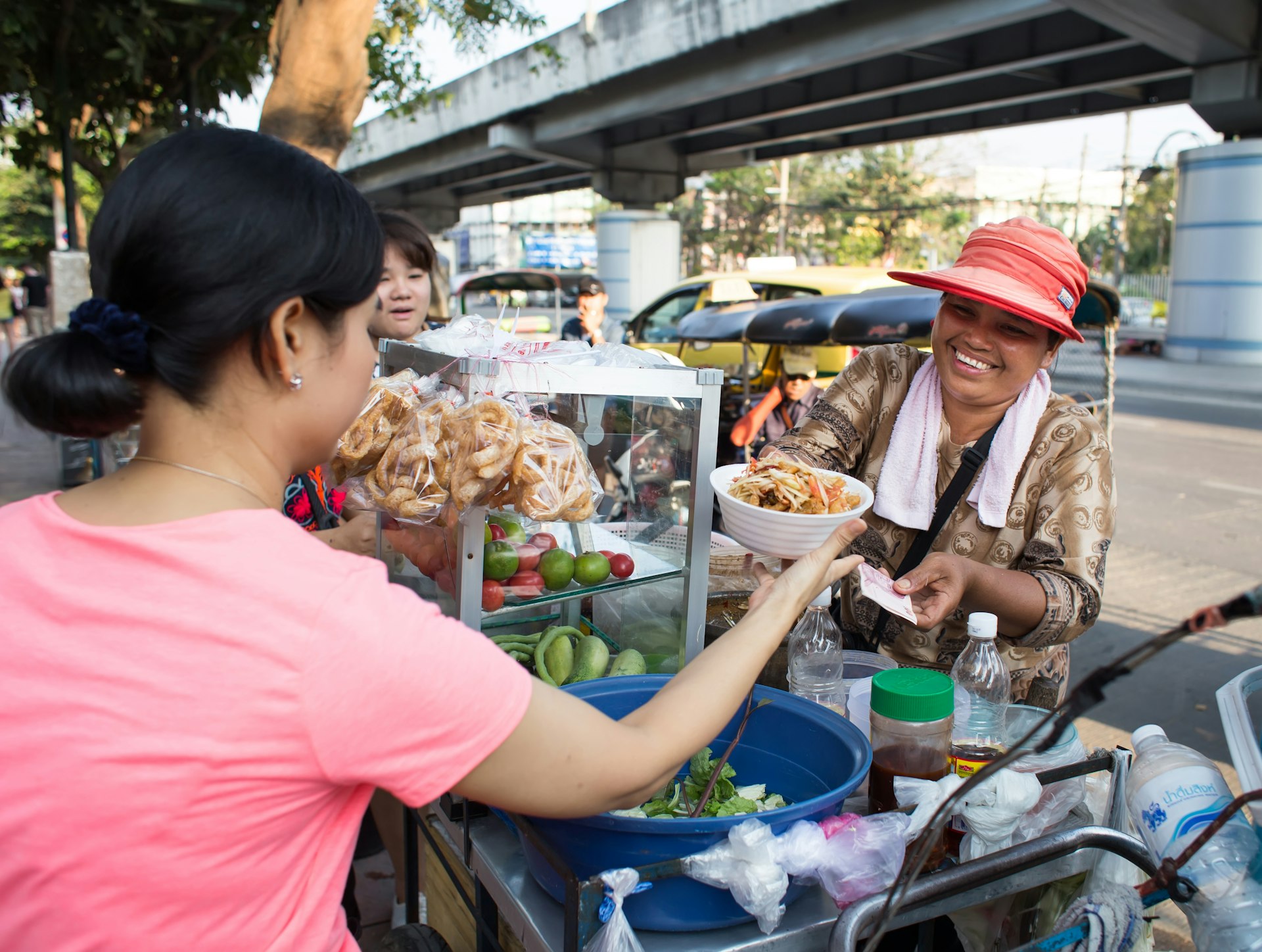 A woman sells papaya salad on the street of Bangkok to another woman. 