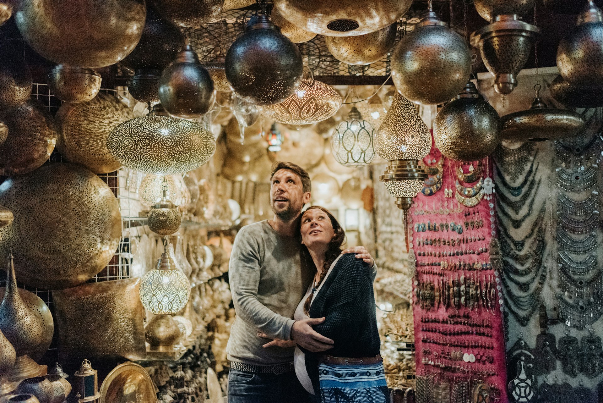 a woman and a man a couple stand in a lamp shop in Marrakech the woman is pregnant both smiling taking in all the lights