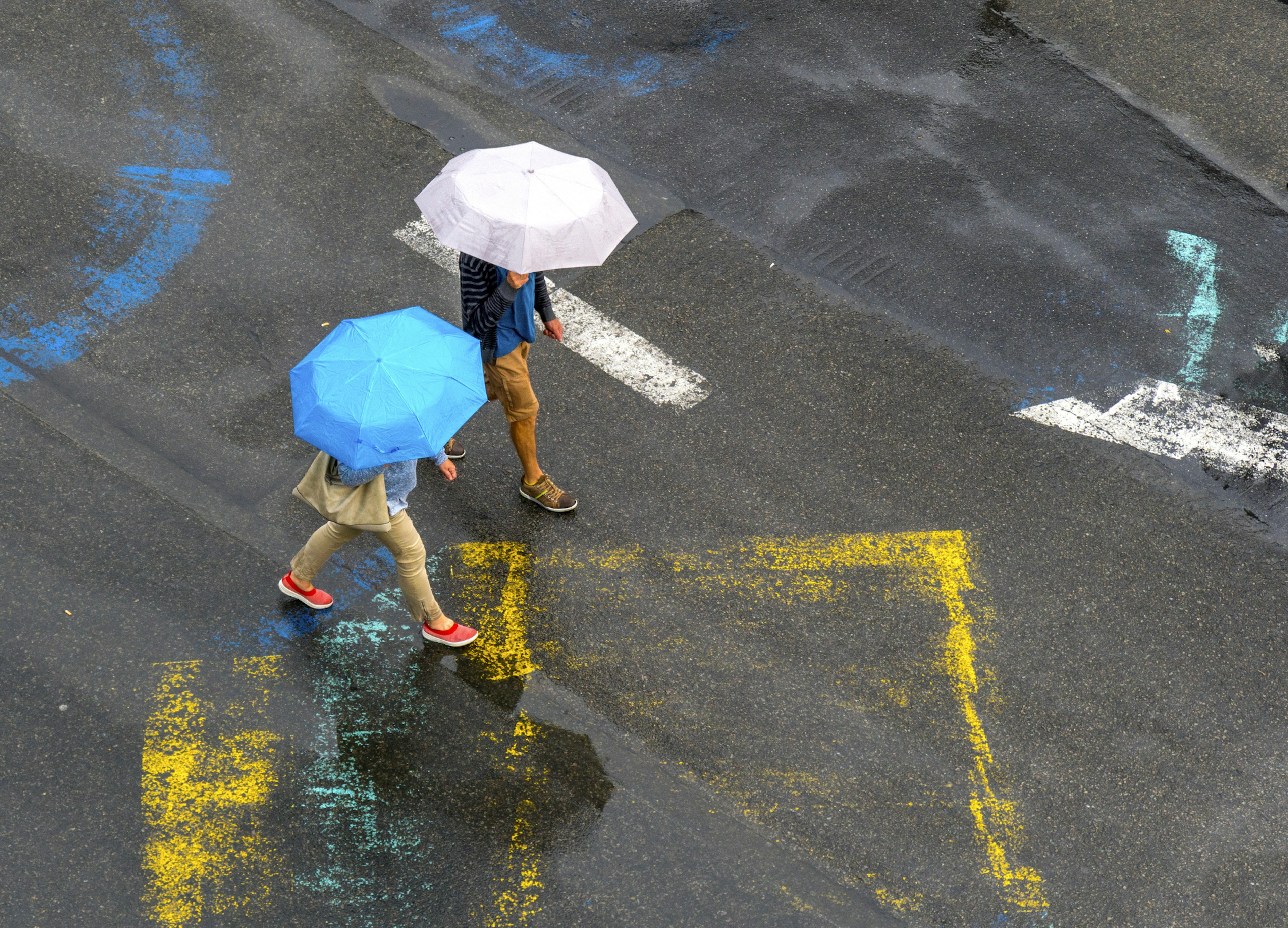 High-angle view of a wet street and two people walking with umbrellas in Brussels