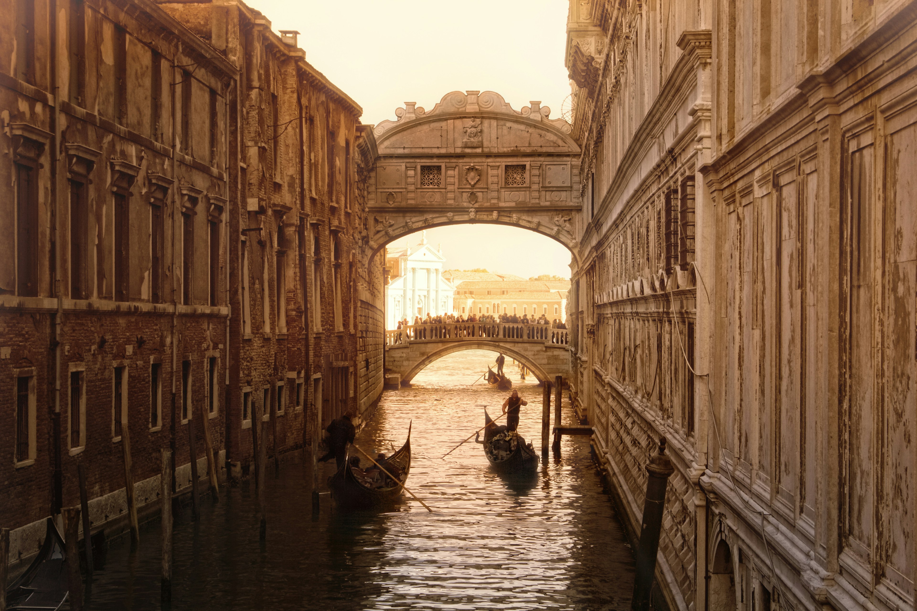 Several gondolas offer their tourist services very early in a new day of the beautiful city of Venice as they punt beneath the Bridge of Sighs