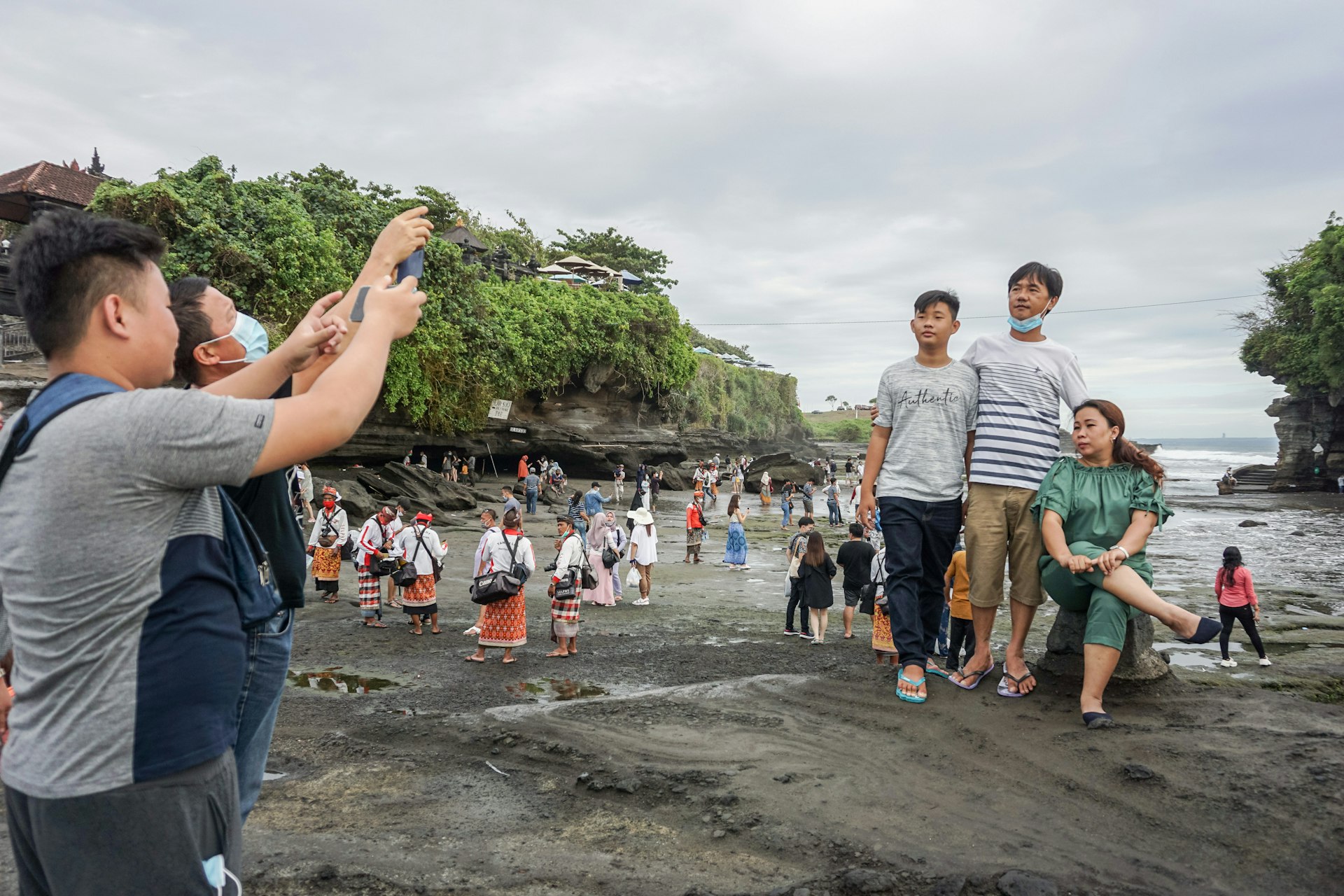 A family takes photographs with the background of the Tanah Lot temple, Tabanan, Bali, Indonesia