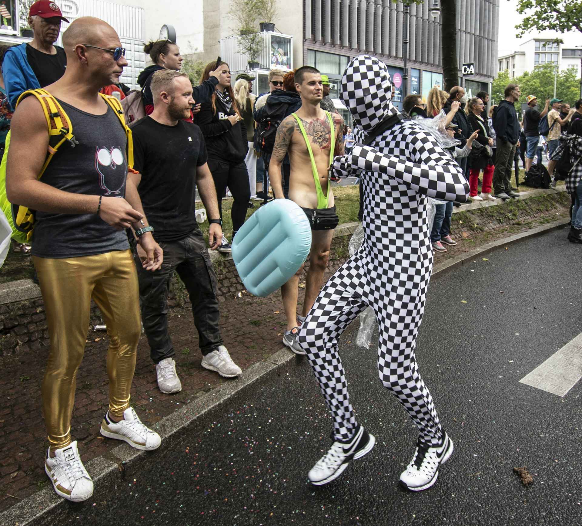A man in a checkered suit and mask dances with others at Rave the Planet (Love Parade) 2022, Berlin, Germany