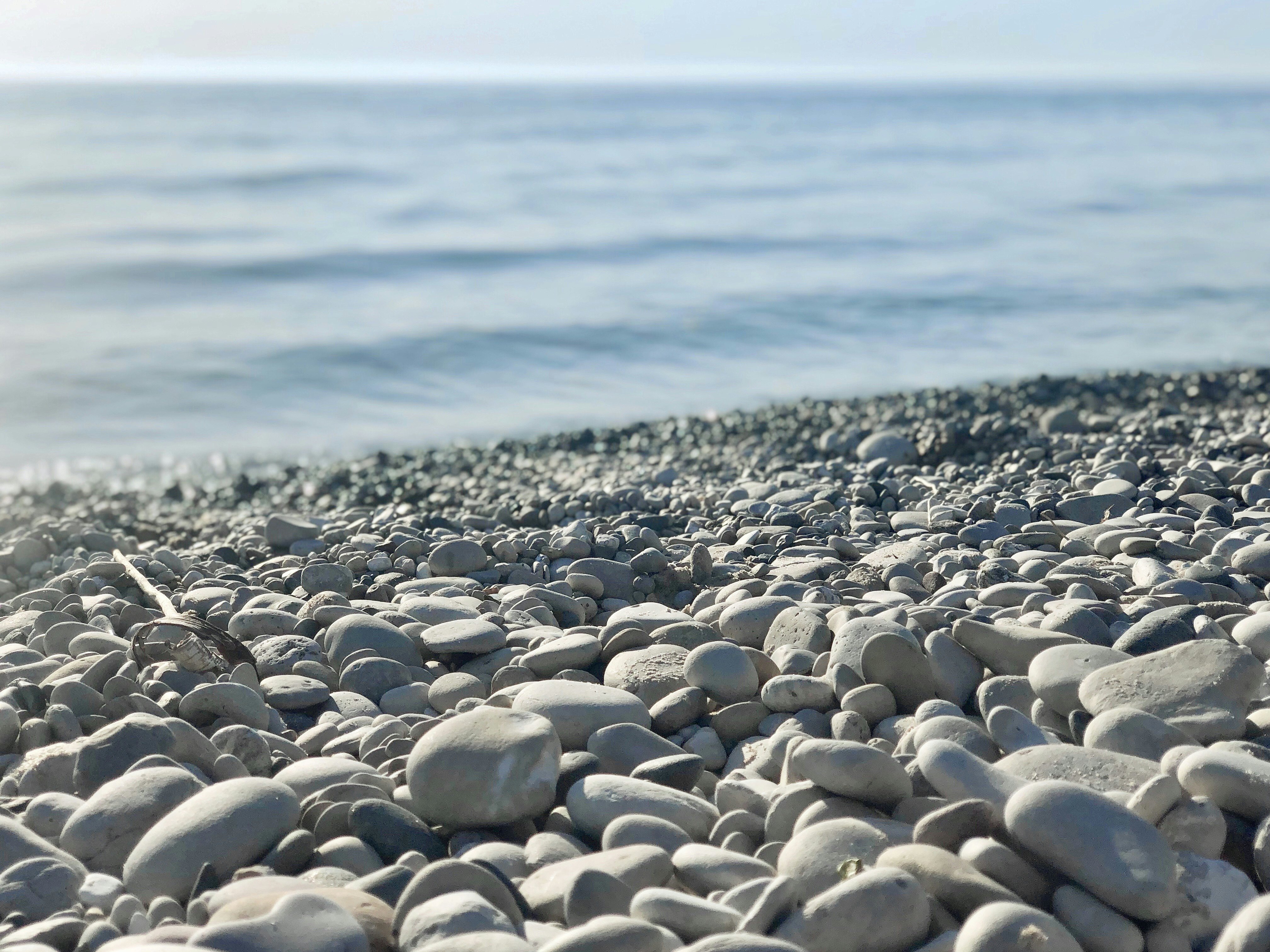 Closeup on smooth stones at Empire Beach in Michigan with waves in the distance