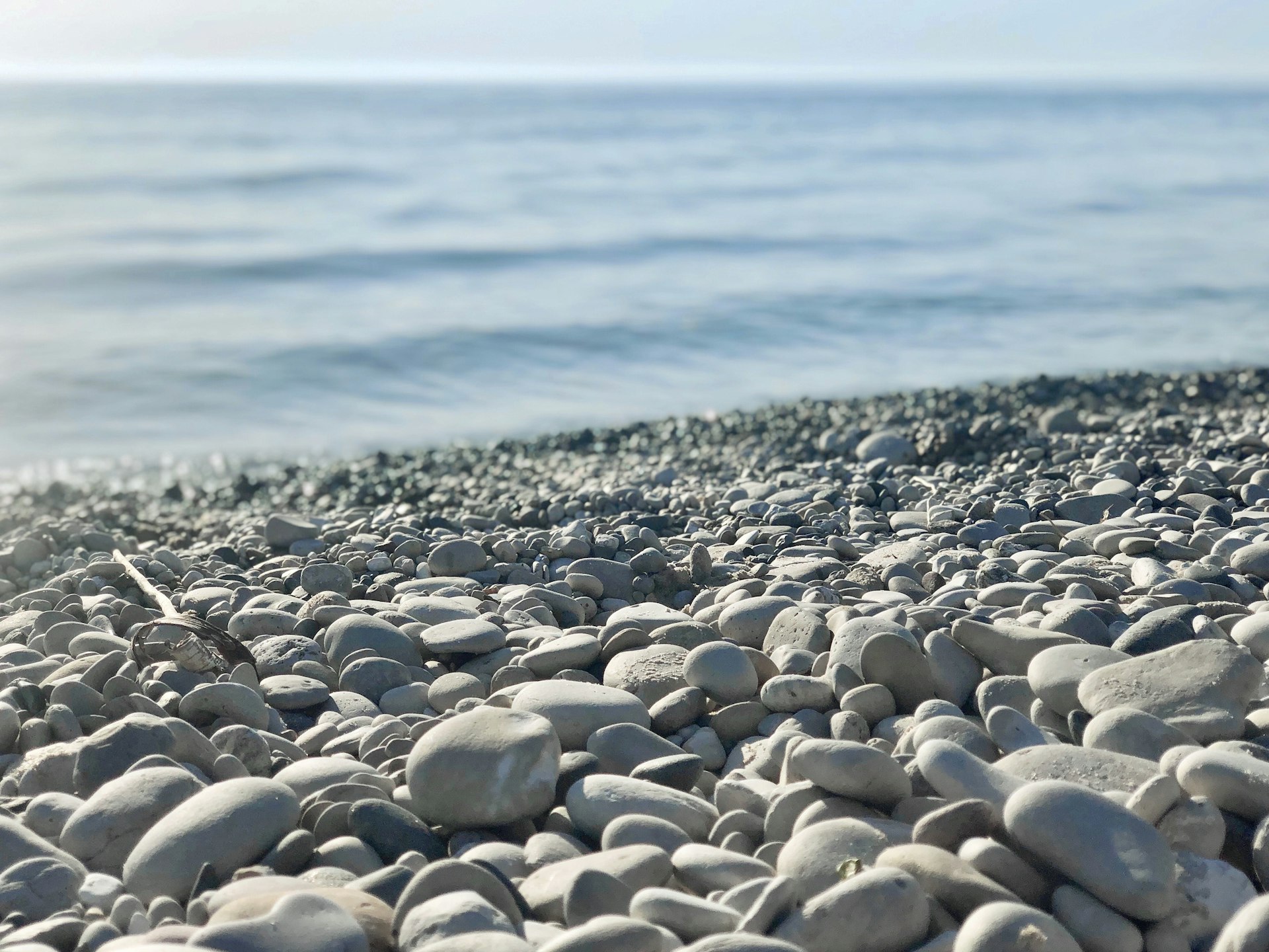 Closeup on smooth stones at Empire Beach in Michigan with waves in the distance