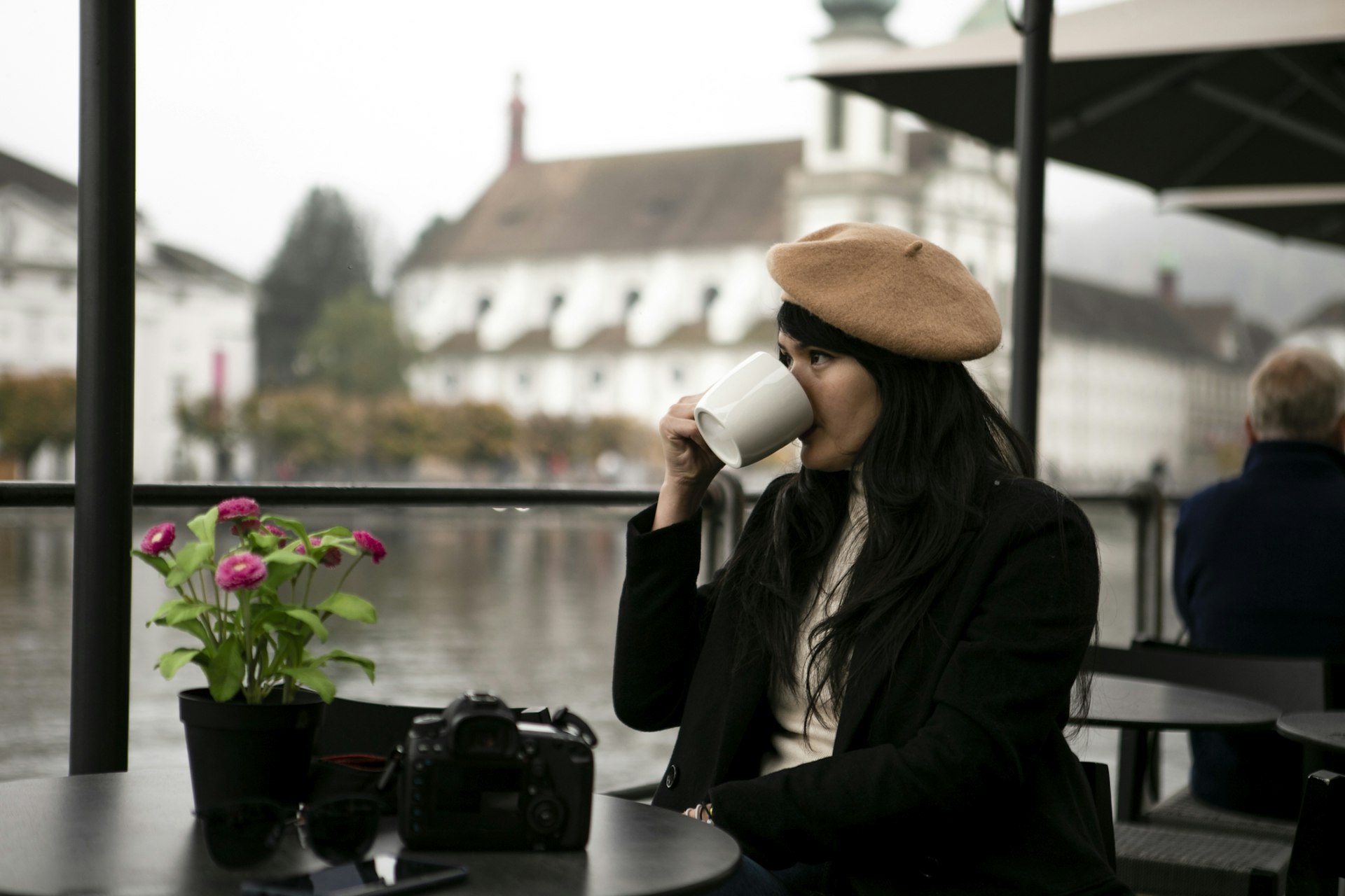 A woman sat at an outdoor table in Lausanne drinking for a mug