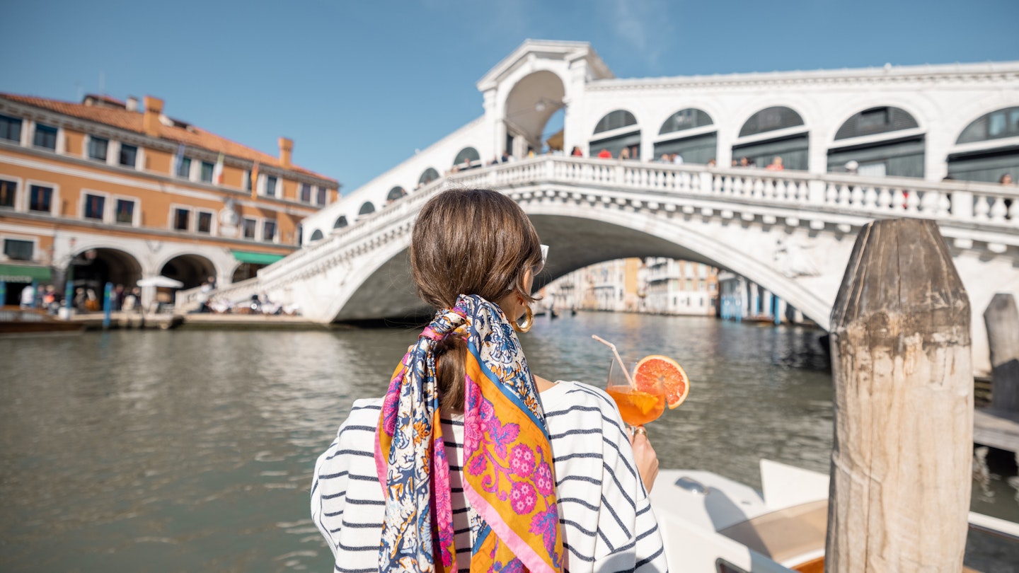 Young woman enjoying summer cocktail on the background of famous Rialto bridge in Venice. Concept of happy vacation and leisure time in Italy. Standing back with italian alcohol drink spritz Aperol
1391067772