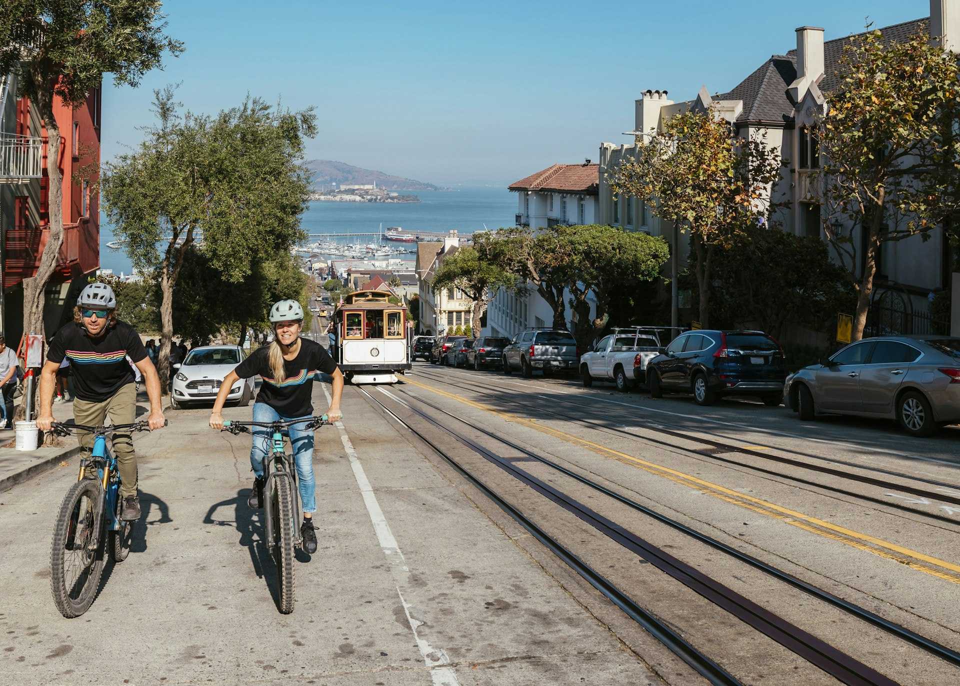 Dos ciclistas van cuesta arriba en San Francisco cuando un tranvía los adelanta hacia la costa