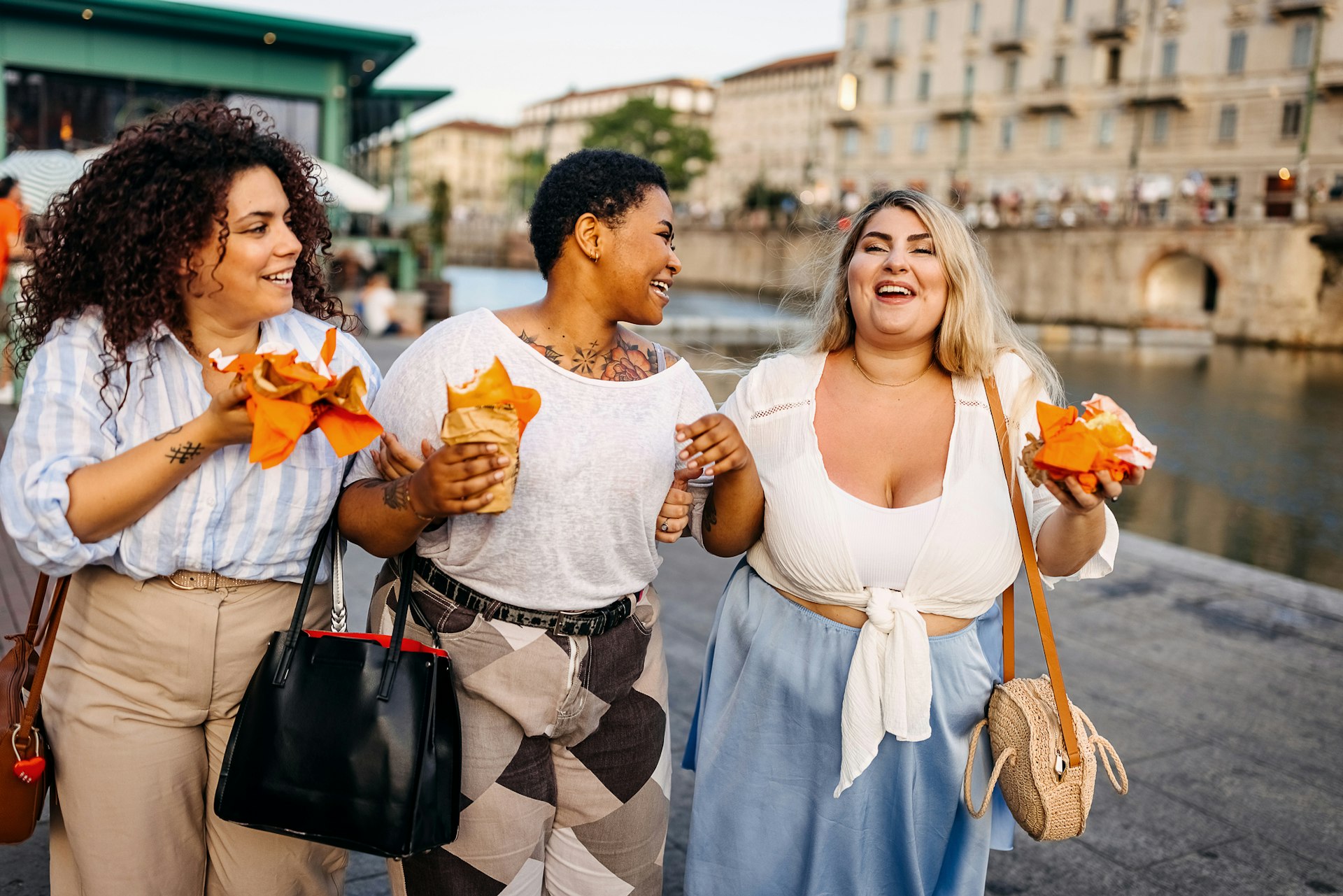 Three women eating fast food as they walk along a street in Italy