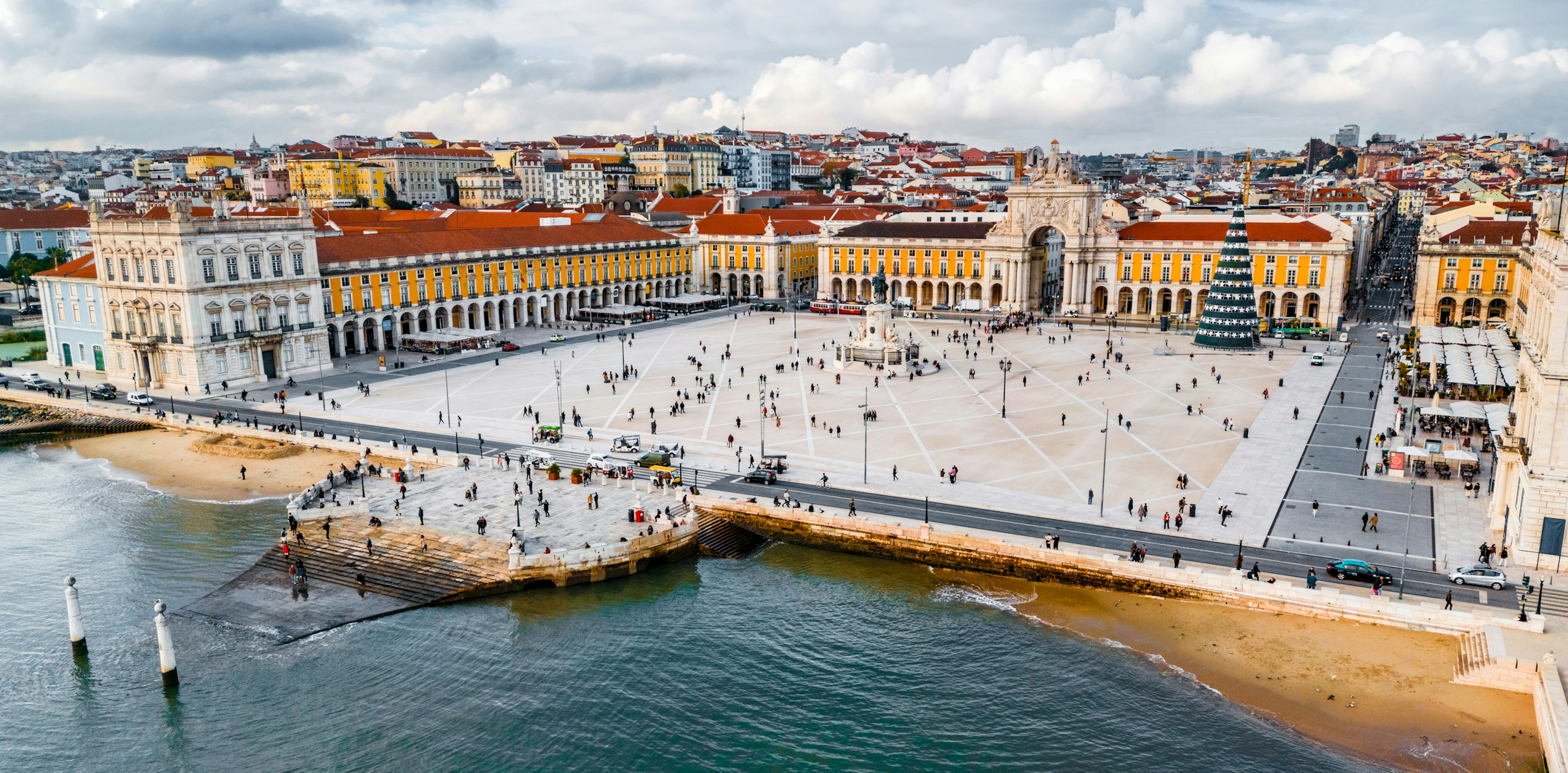 A large city square by a river in winter, with some people moving around