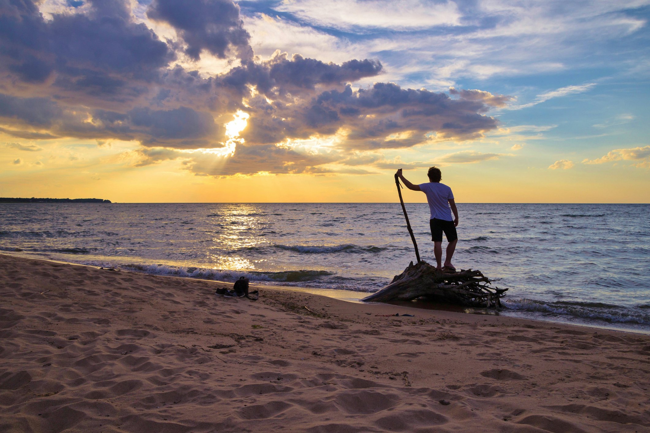 Young adult male on the beach greets the dawn of a new day