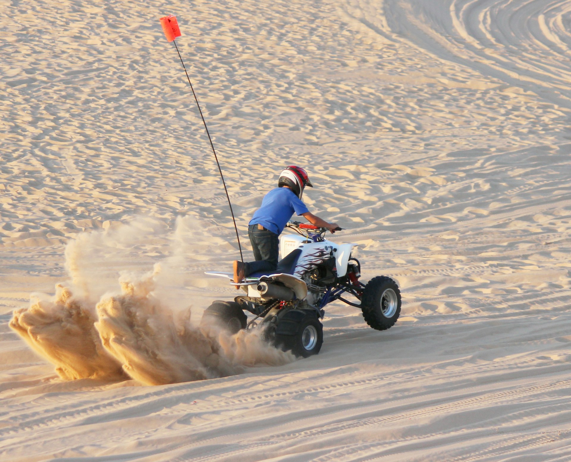 A quad rider doing a burnout on the sand in Michigan