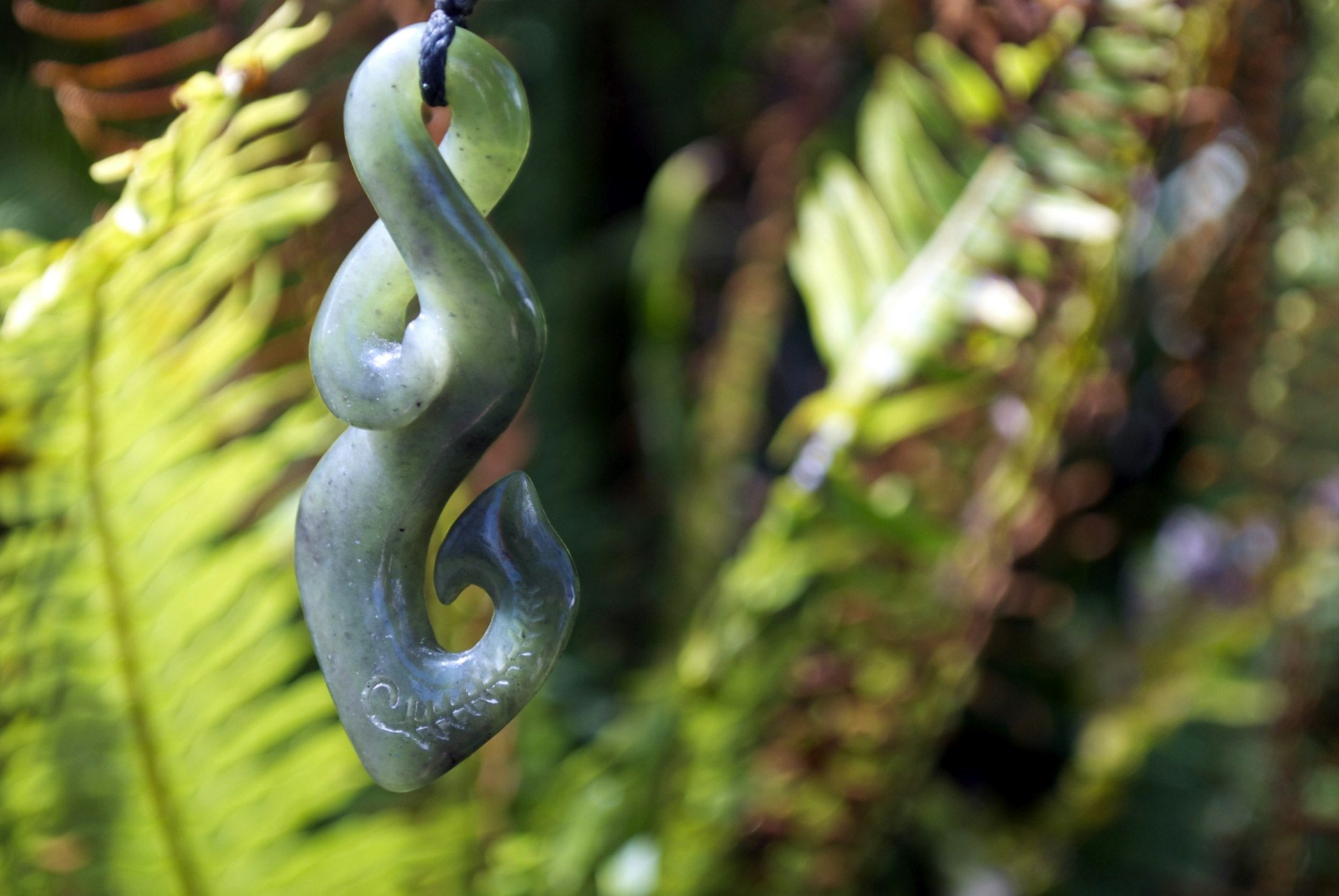 A greenstone carved pendant with a loop, twist and hook on the end