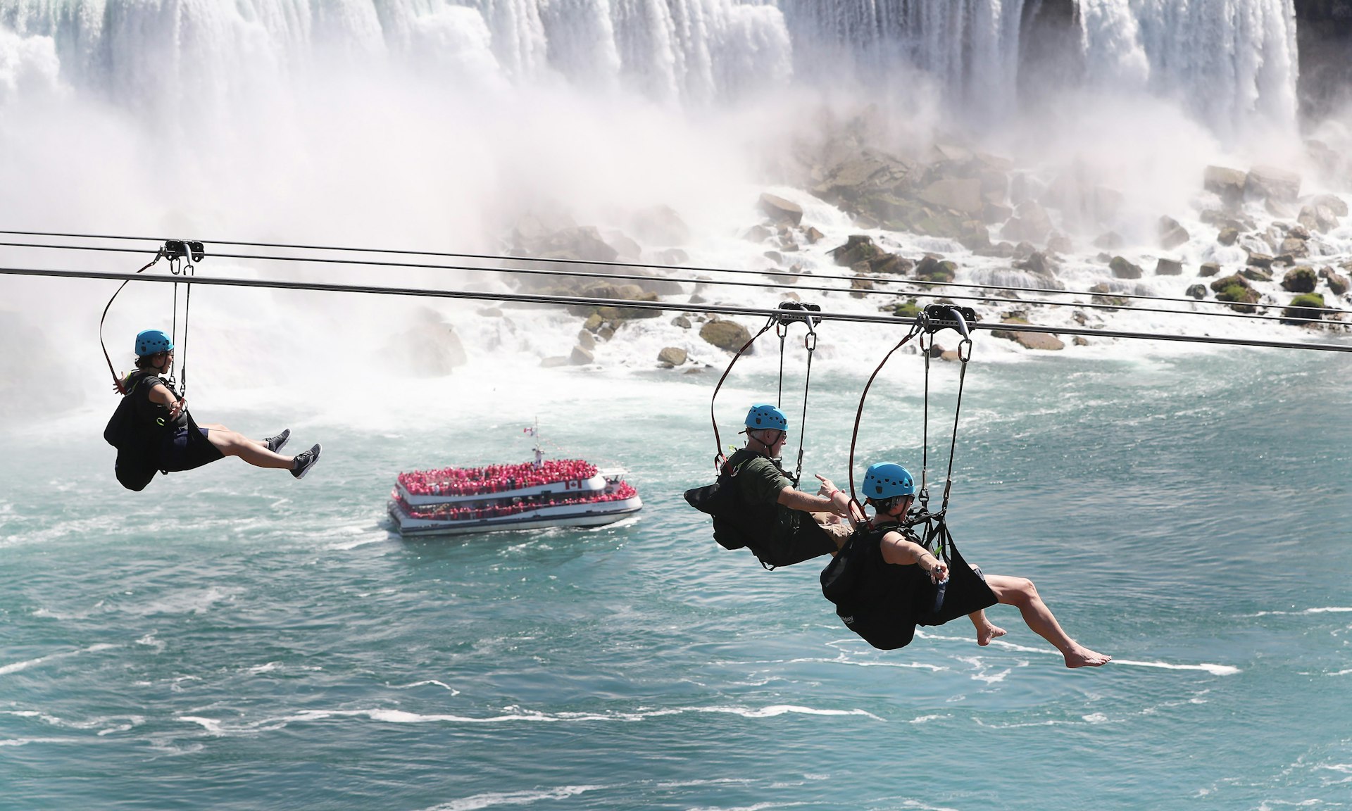 People clipped into a zip line pass over Niagara Falls, Ontario, Canada