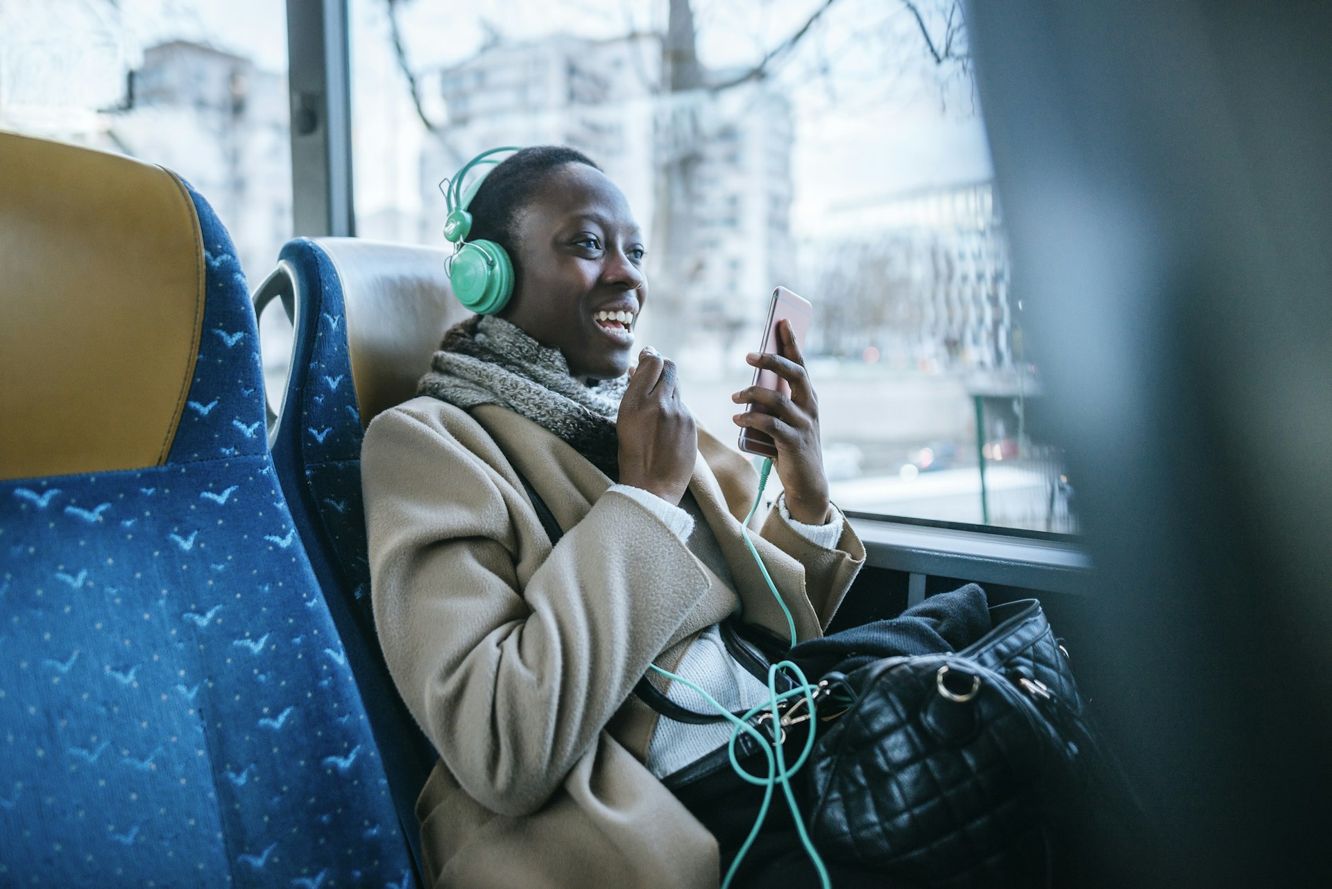 A young woman using headphones and smartphone on the stop floor of a bus in France