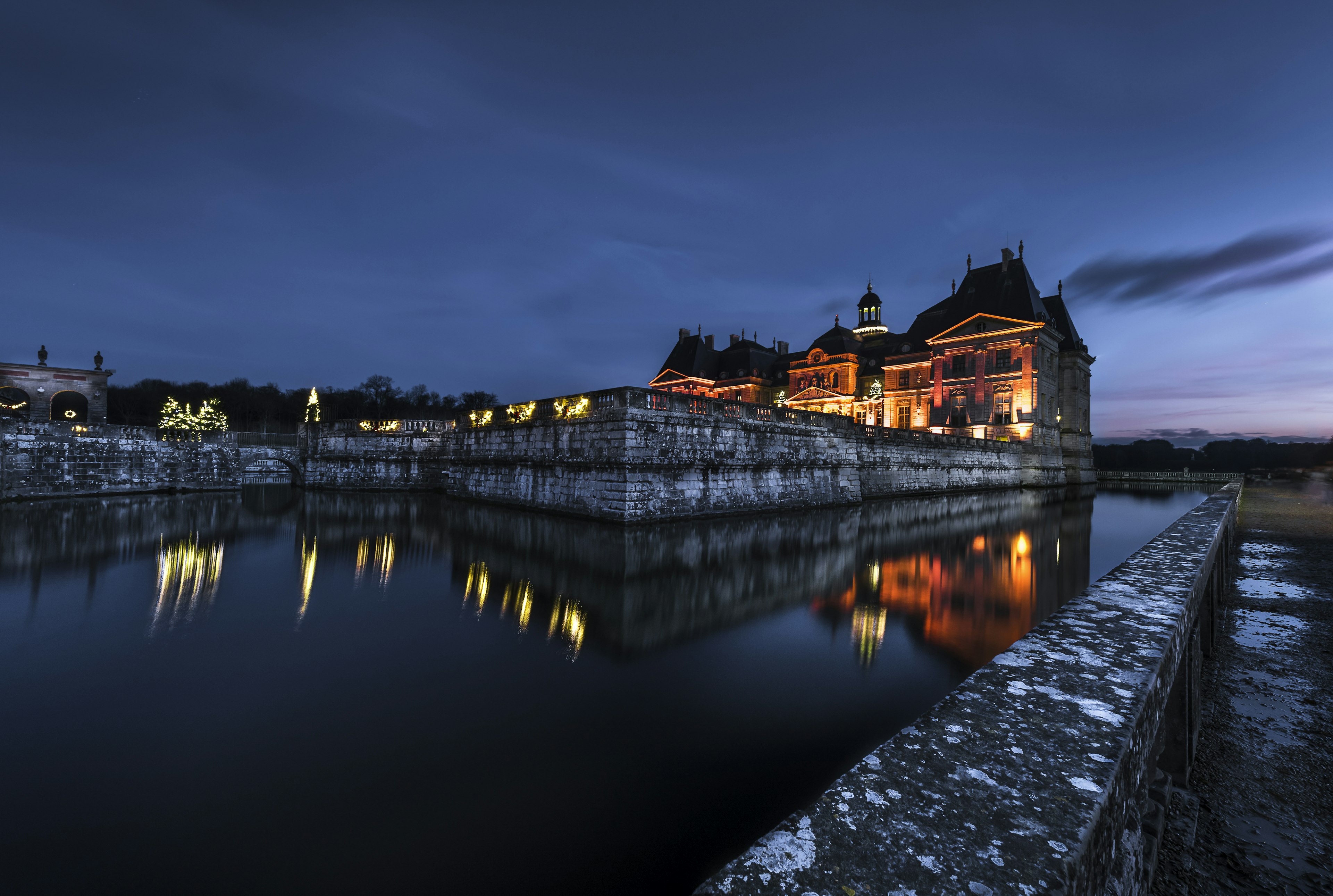 The baroque Chateau de Vaux-le-Vicomte reflected in moats at twilight