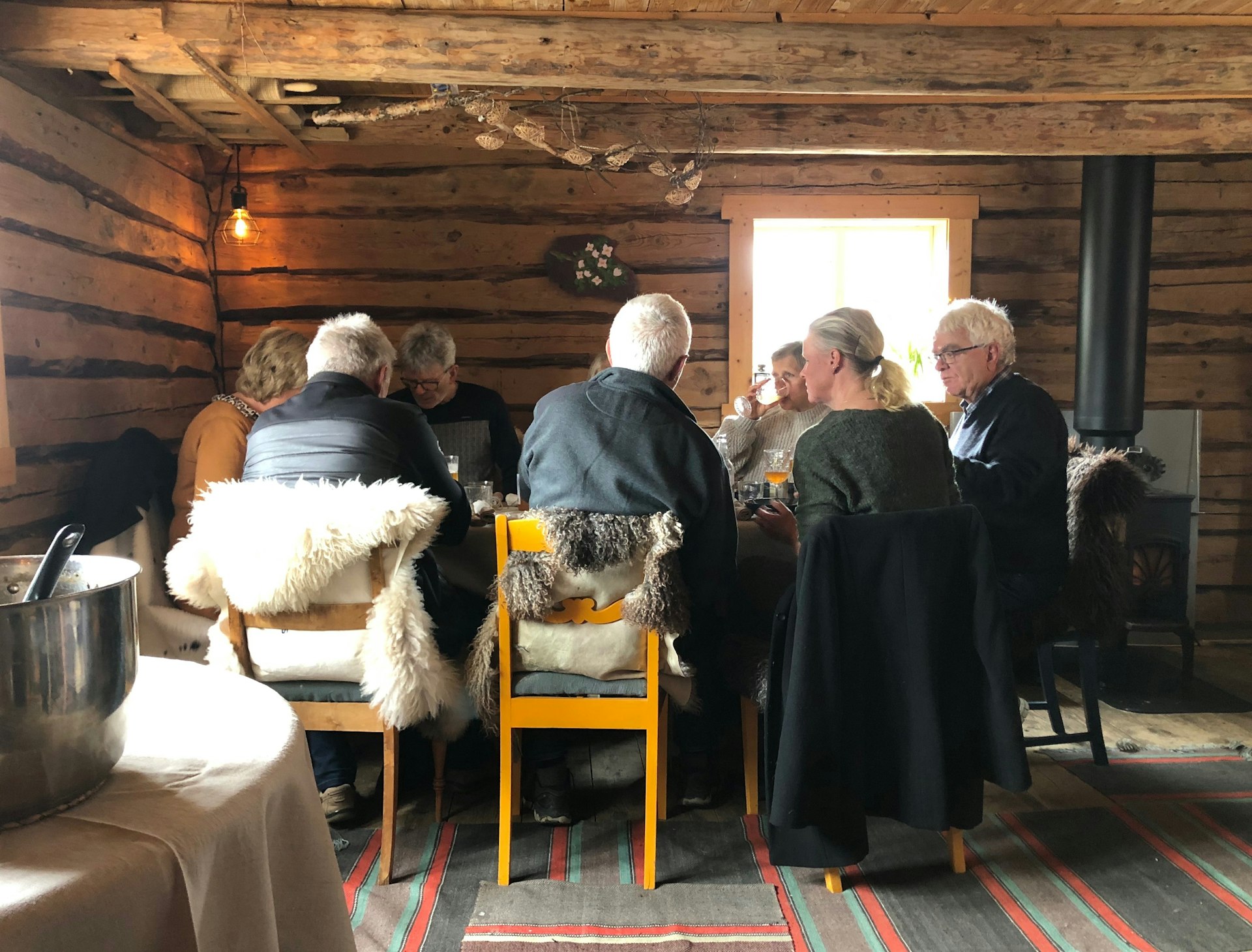 Diners sit at a table in a barn for lunch at Skølberg Søndre farm, Trøndelag, Norway