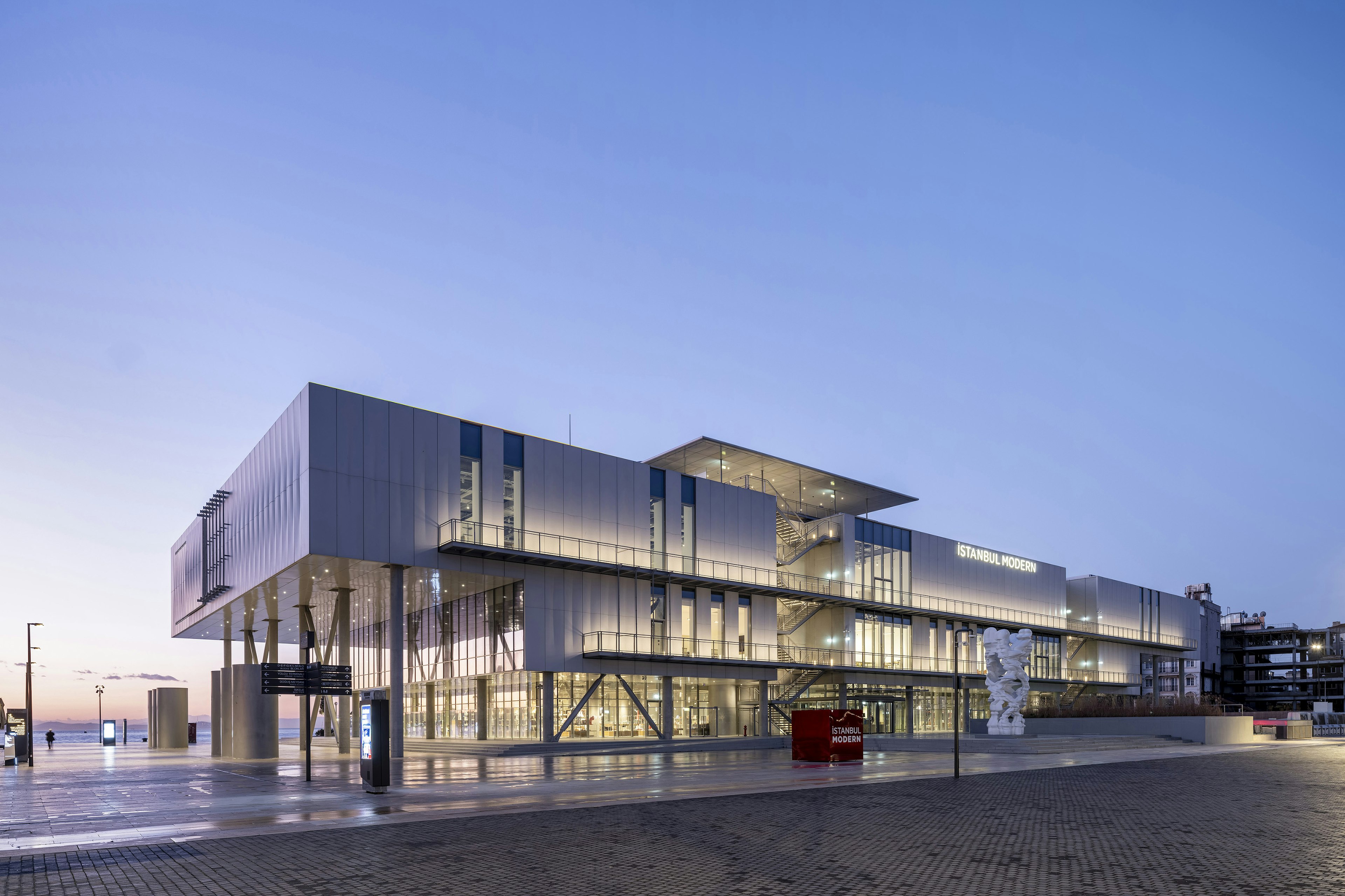 The facade of Renzo Piano's new Istanbul Modern, shot from a side angle and lit up at dusk