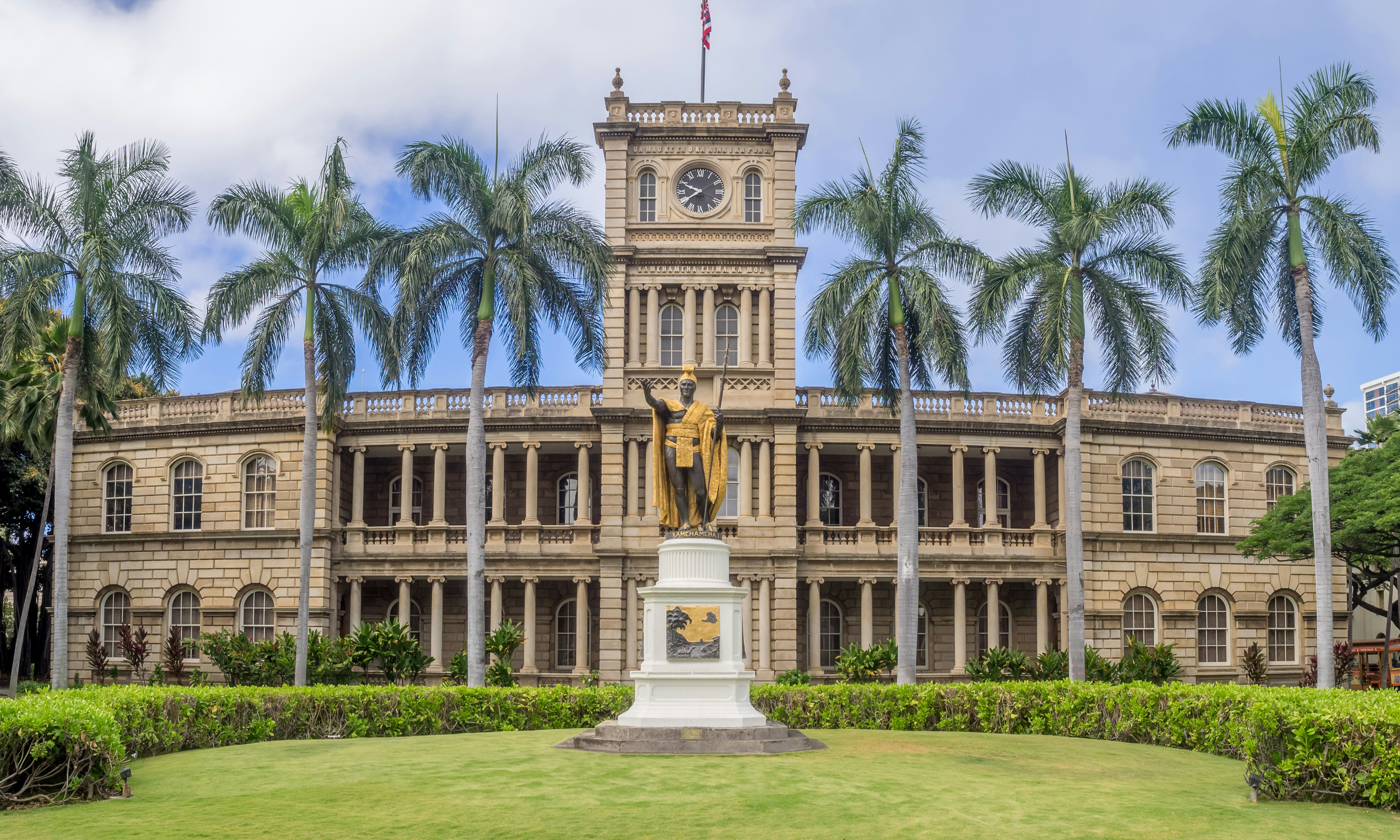 The exterior of a large palace building with a palm-tree-lined garden