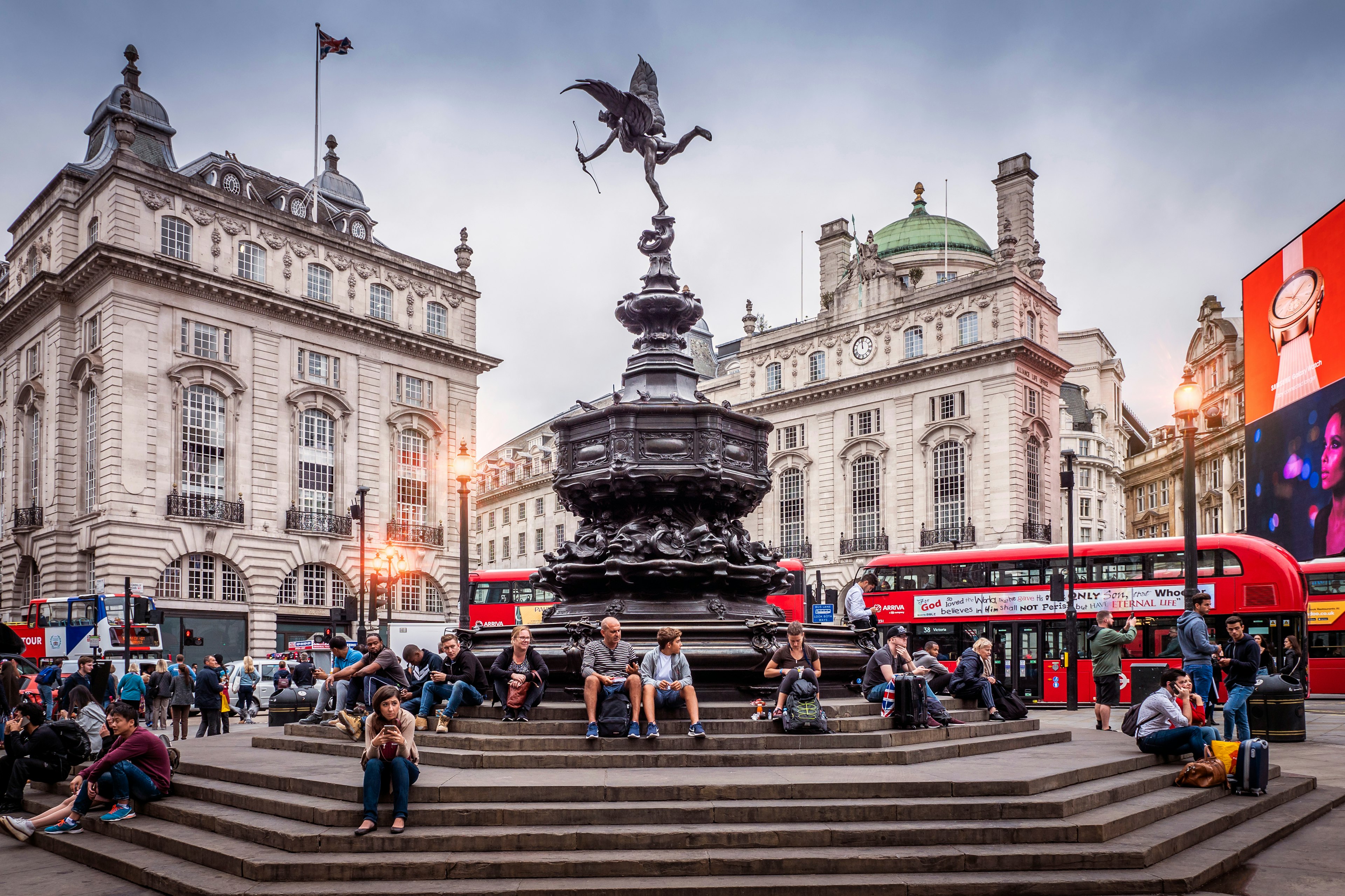 The historic architecture of London in the United Kingdom at sunset showcasing Piccadilly Circus with lots of locals and tourists passing by.