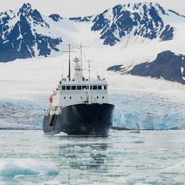 Exploration boat in front of Lilliehook glacier in Lilliehook fjord, a branch of Cross Fjord, Spitsbergen Island, Svalbard archipelago, Norway.