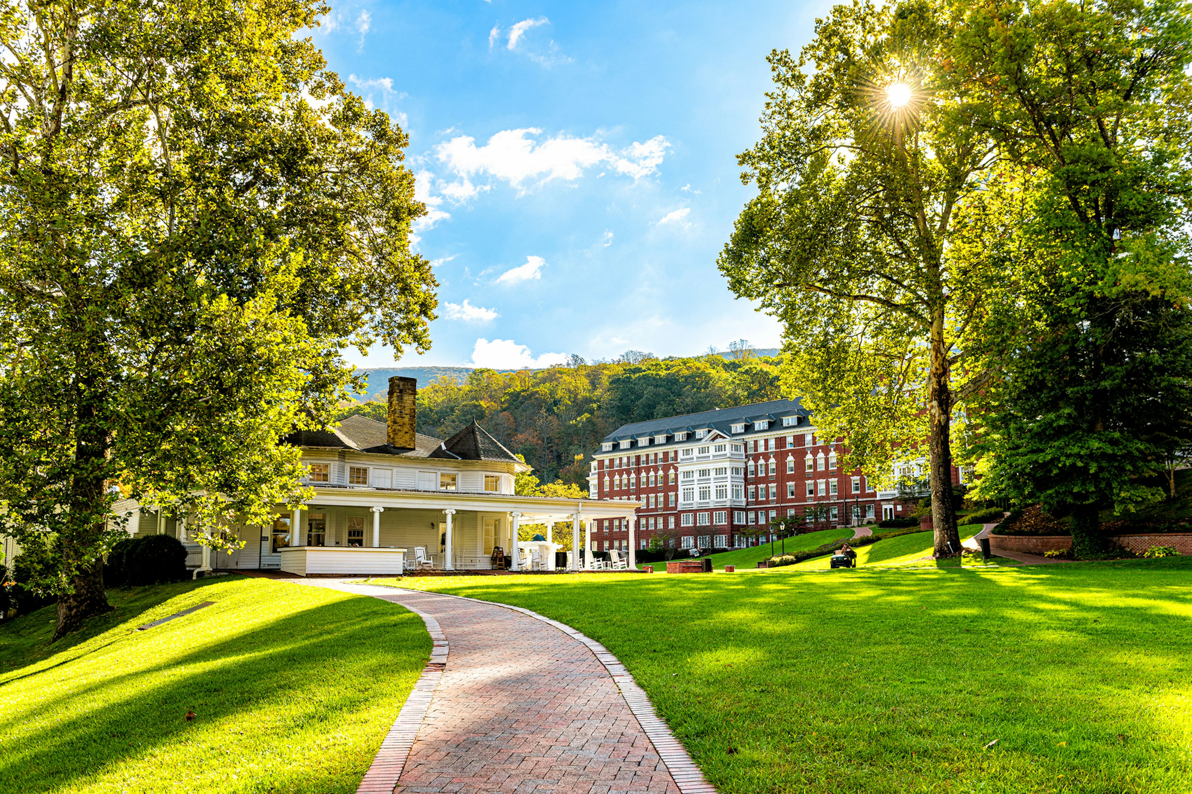 The exterior of a grand red-brick hotel in vast landscaped gardens