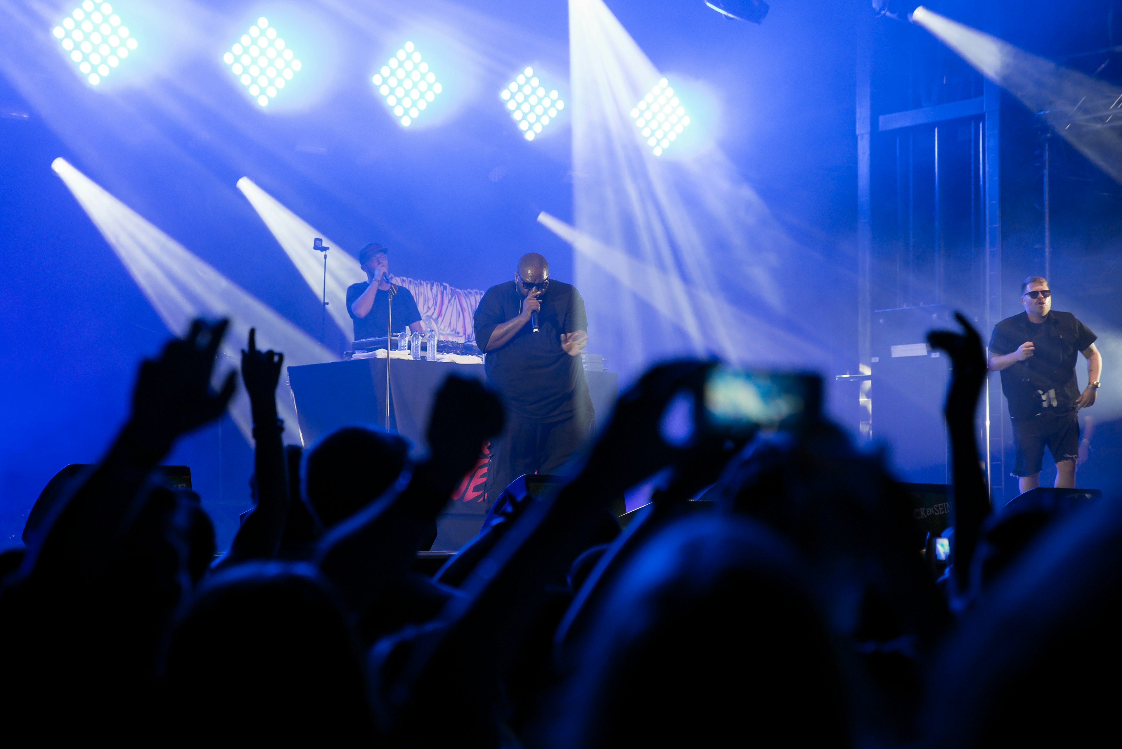 Two performers on stage are bathed in blue spotlights in front of a crowd