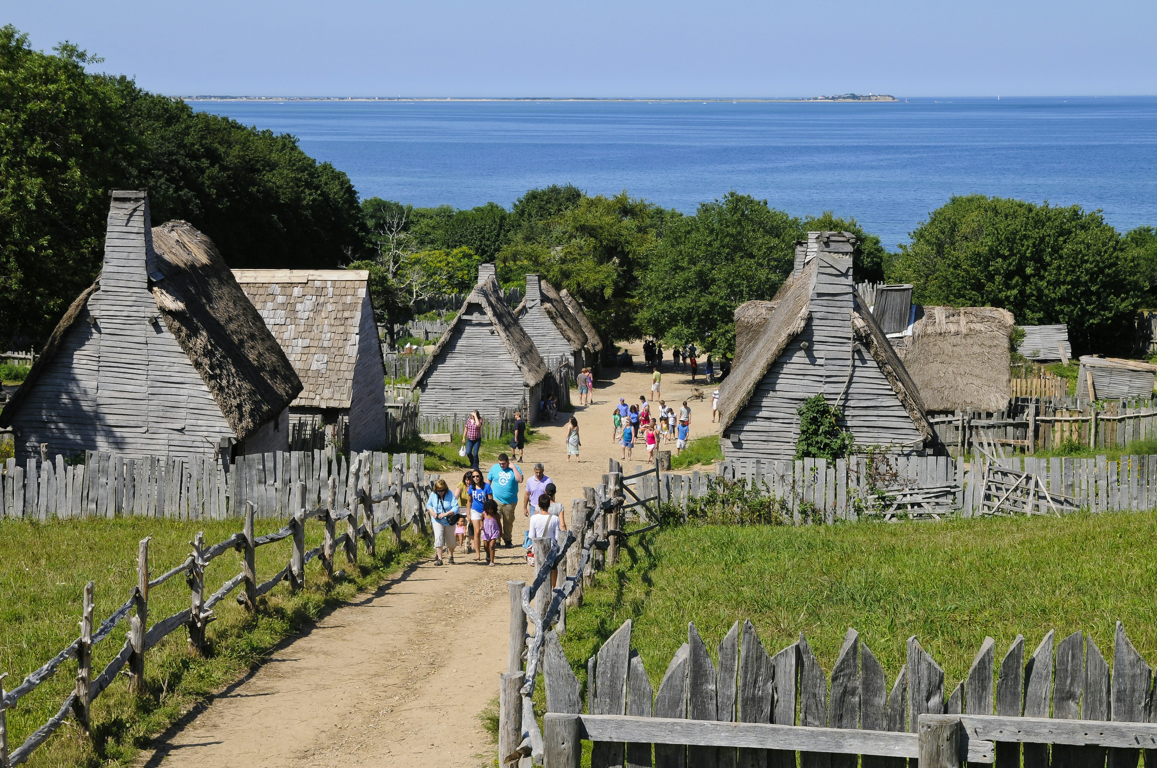 A village of small wooden houses by the sea with tourists wandering among them