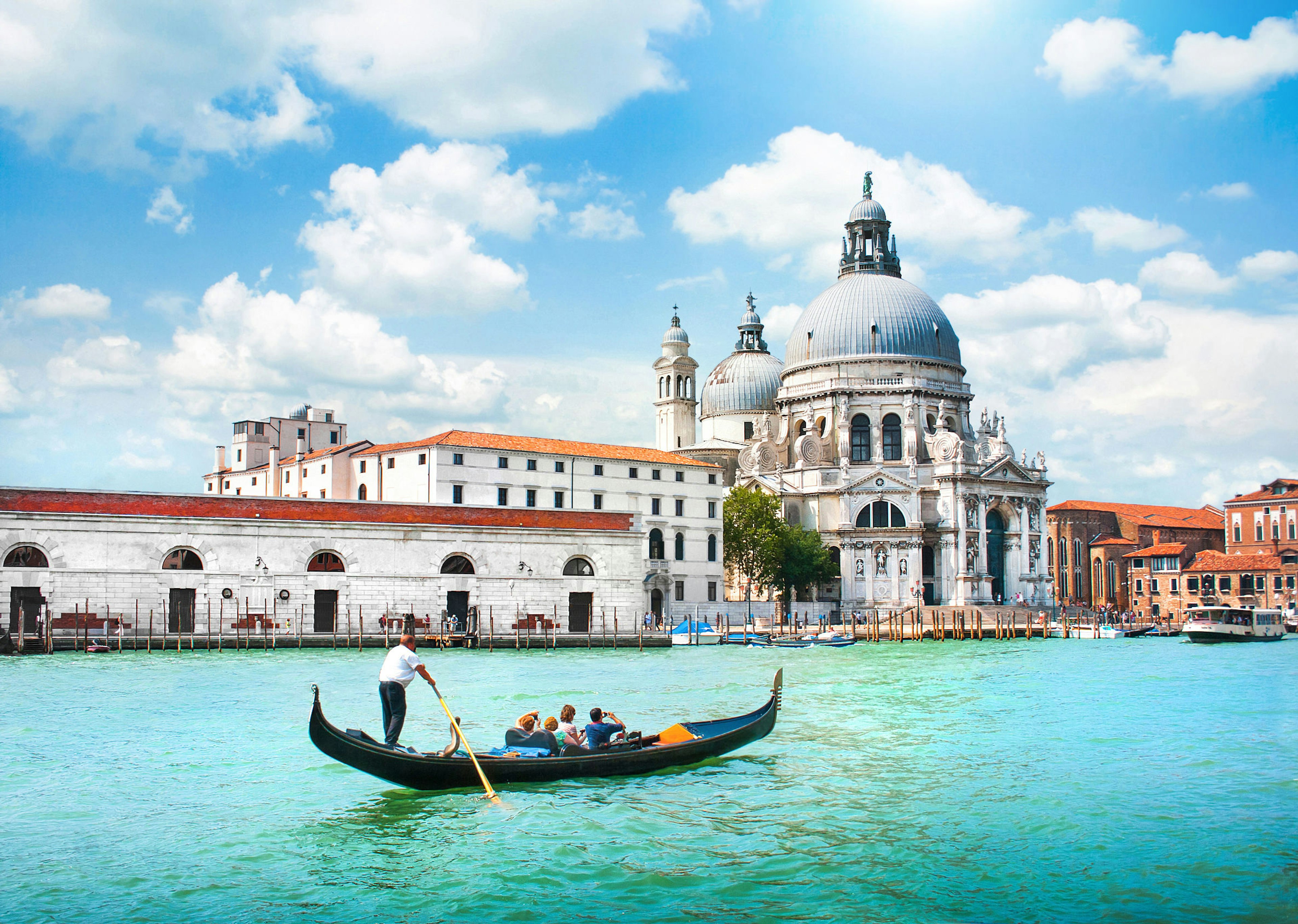 Gondola being guided along a canal with a large domed church in the background