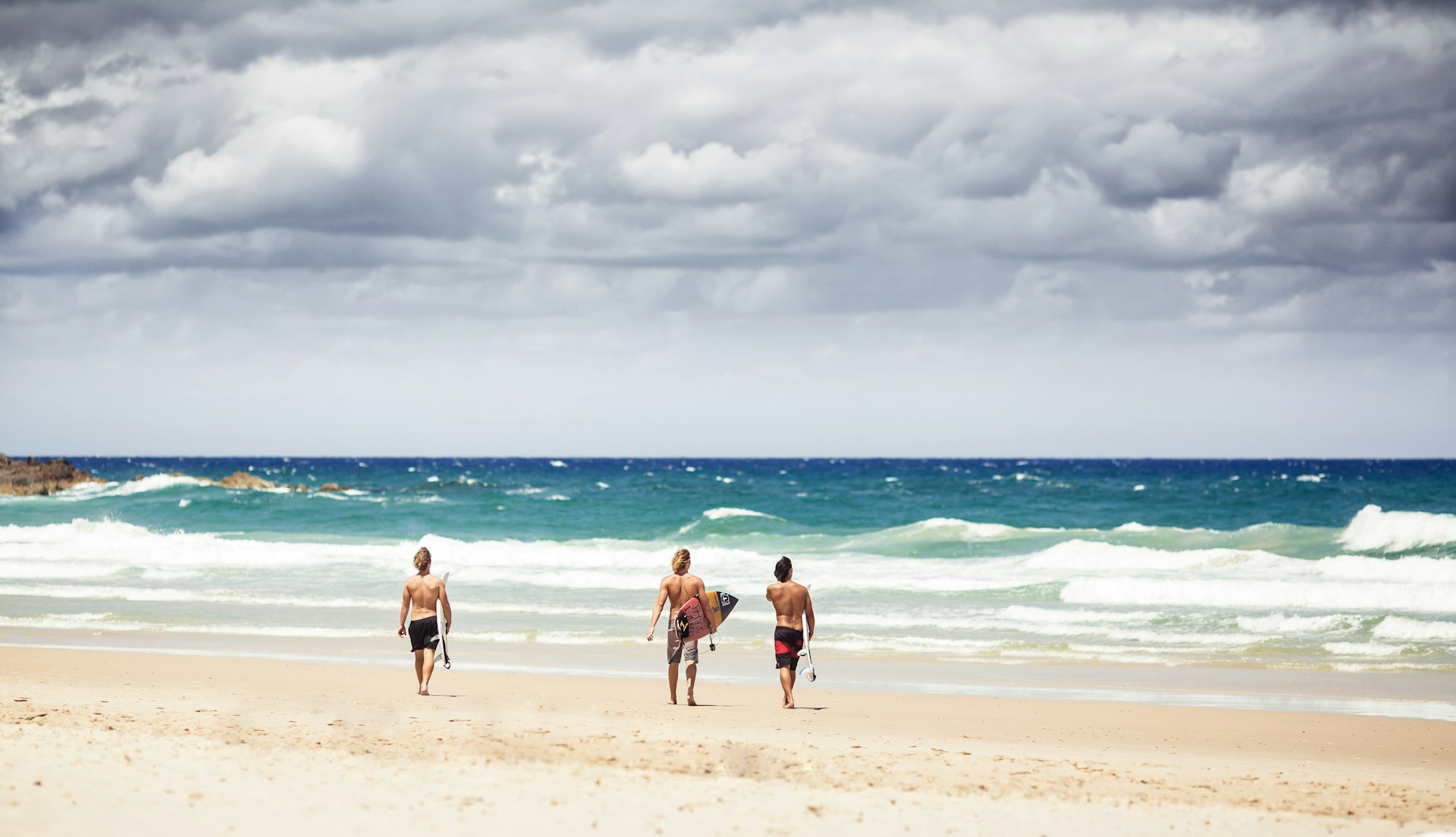 Surfers goes into the water with surfboards on Byron Bay beach in New South Wales.