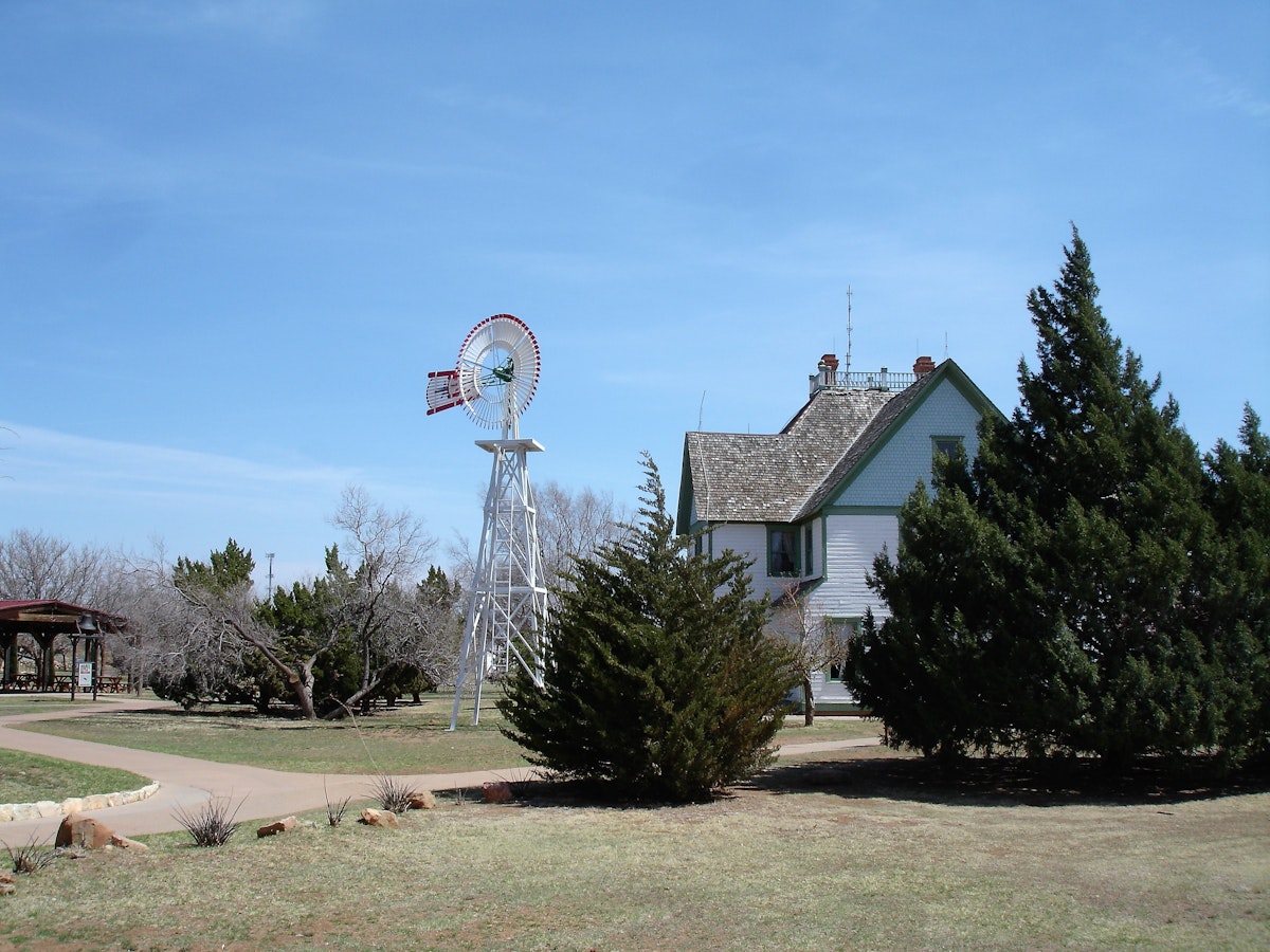 Water pumping windmill next to a historic house at the National Ranching Heritage Center in Lubbock, Texas.