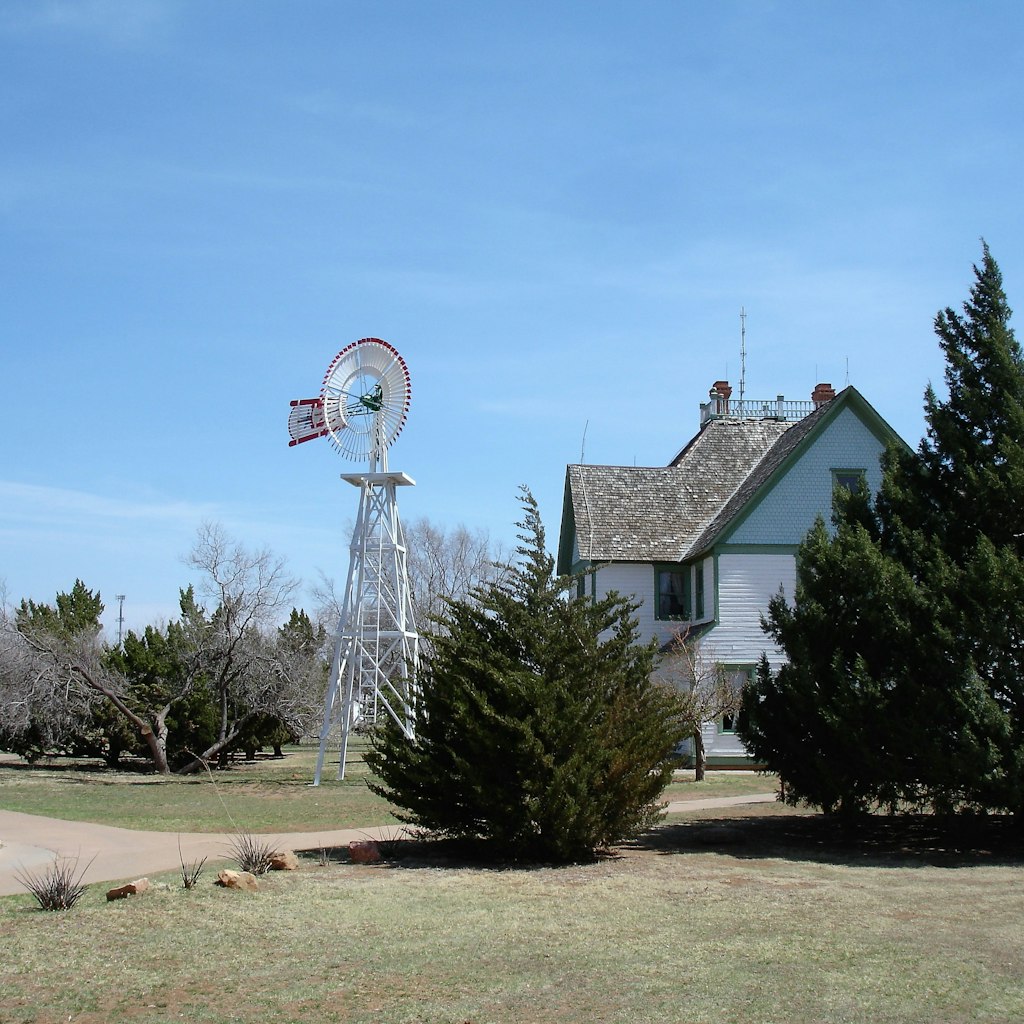 Water pumping windmill next to a historic house at the National Ranching Heritage Center in Lubbock, Texas.