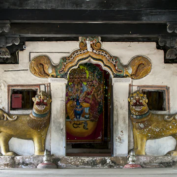 The entrance to the main shrine at Embekka Devale is located at the end of the digge (drummers pavilion) through a door guarded by lion statues.
