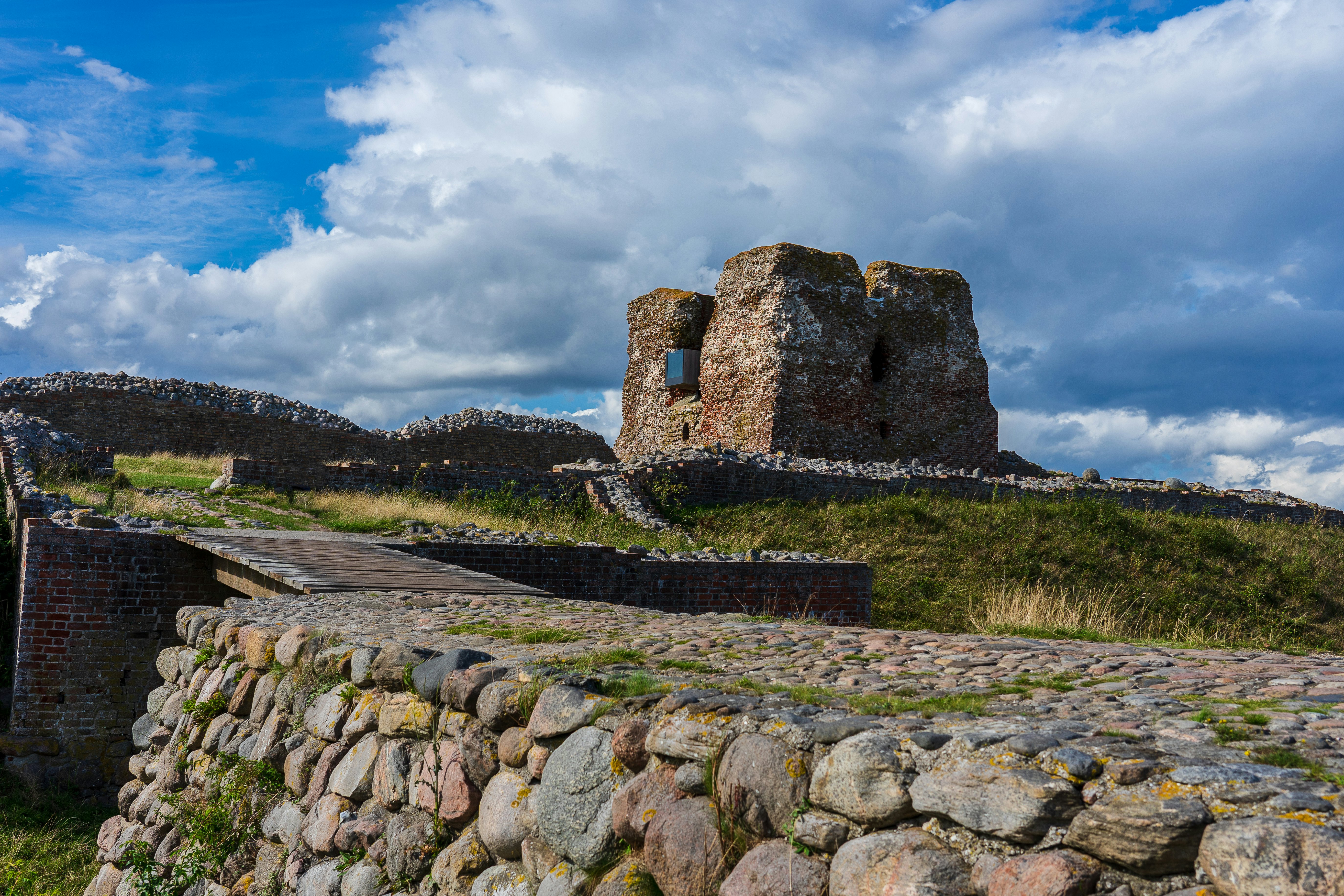 The remains of the historic danish fortress known as "Kalø Slotsruin" from the bridge leading to the old entrance with the big tower still standing tall.