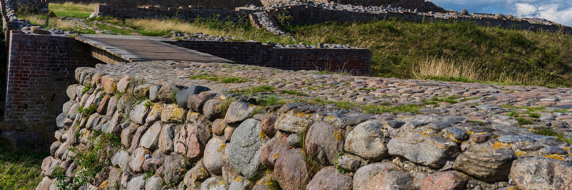 The remains of the historic danish fortress known as "Kalø Slotsruin" from the bridge leading to the old entrance with the big tower still standing tall.